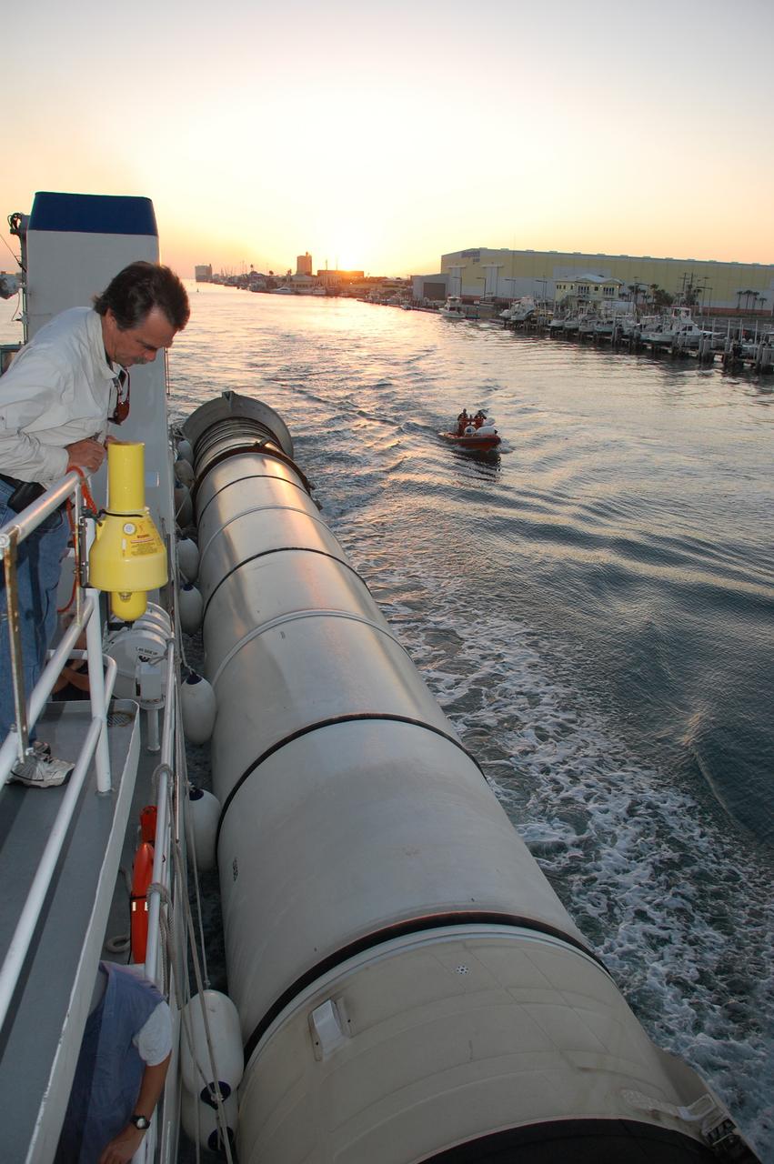 CAPE CANAVERAL, Fla. -- As daylight breaks, Walt Adams, a space shuttle solid rocket booster retrieval and dive supervisor, monitors a spent booster as it's towed by the Freedom Star retrieval ship through Port Canaveral in Florida on a journey to Hangar AF at Cape Canaveral Air Force Station. The booster was used during space shuttle Discovery's STS-133 launch from NASA Kennedy Space Center's Launch Pad 39A on Feb. 24. The shuttle’s two solid rocket booster casings and associated flight hardware are recovered in the Atlantic Ocean after every launch by Freedom Star and Liberty Star. The boosters impact the Atlantic about seven minutes after liftoff and the retrieval ships are stationed about 10 miles from the impact area at the time of splashdown.  After the spent segments are processed, they will be transported to Utah, where they will be refurbished and stored, if needed. Photo credit: NASA/Ben Smegelsky