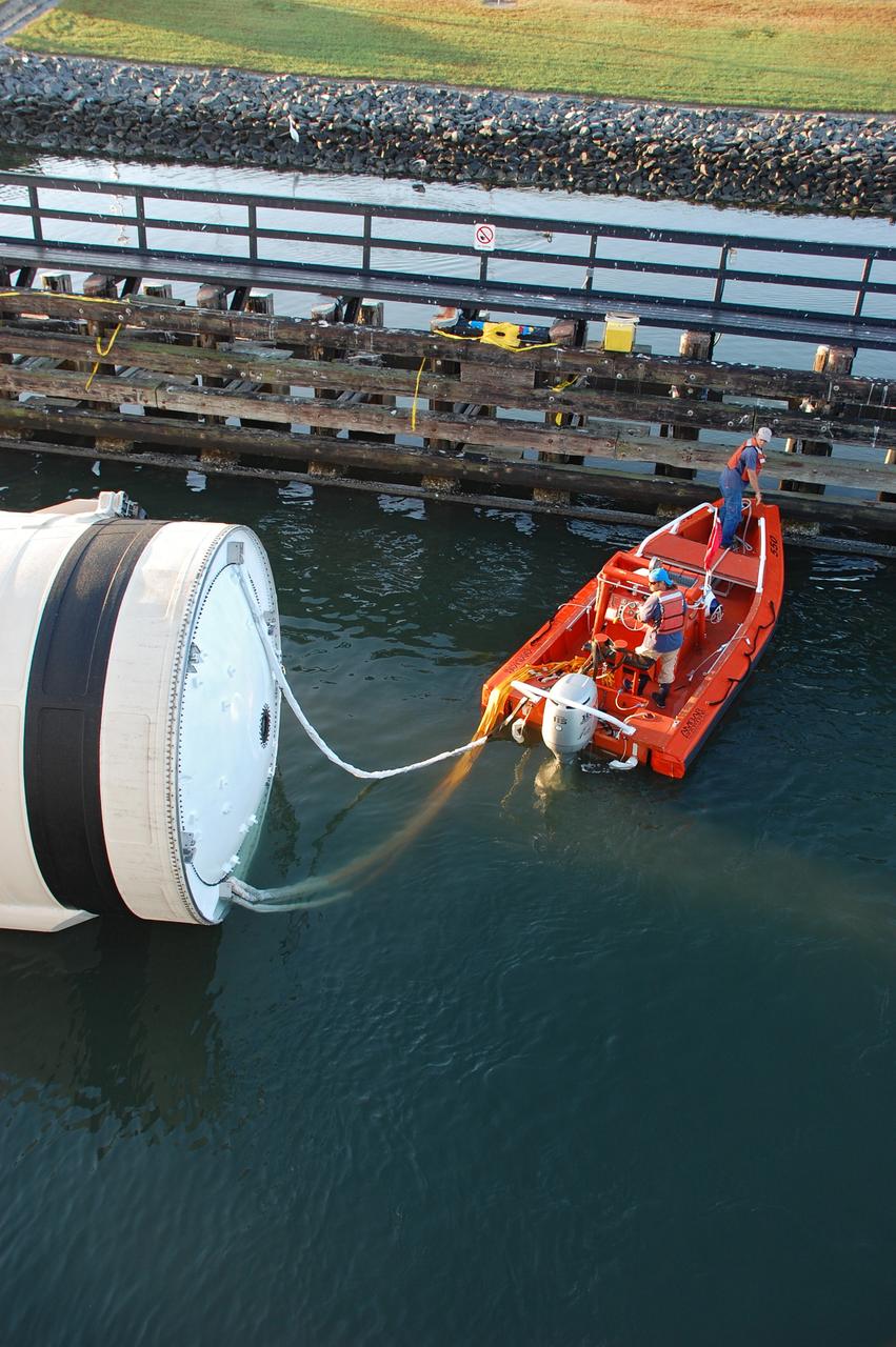 CAPE CANAVERAL, Fla. -- Crew members in a skiff from Freedom Star, one of NASA's solid rocket booster retrieval ships, will usher a spent shuttle booster through the shallow waters of the locks at Port Canaveral, Fla. The booster, which was used during space shuttle Discovery's STS-133 launch from NASA Kennedy Space Center's Launch Pad 39A on Feb. 24, is on its way to Hangar AF at Cape Canaveral Air Force Station. The shuttle’s two solid rocket booster casings and associated flight hardware are recovered in the Atlantic Ocean after every launch by Freedom Star and Liberty Star. The boosters impact the Atlantic about seven minutes after liftoff and the retrieval ships are stationed about 10 miles from the impact area at the time of splashdown.  After the spent segments are processed, they will be transported to Utah, where they will be refurbished and stored, if needed. Photo credit: NASA/Ben Smegelsky