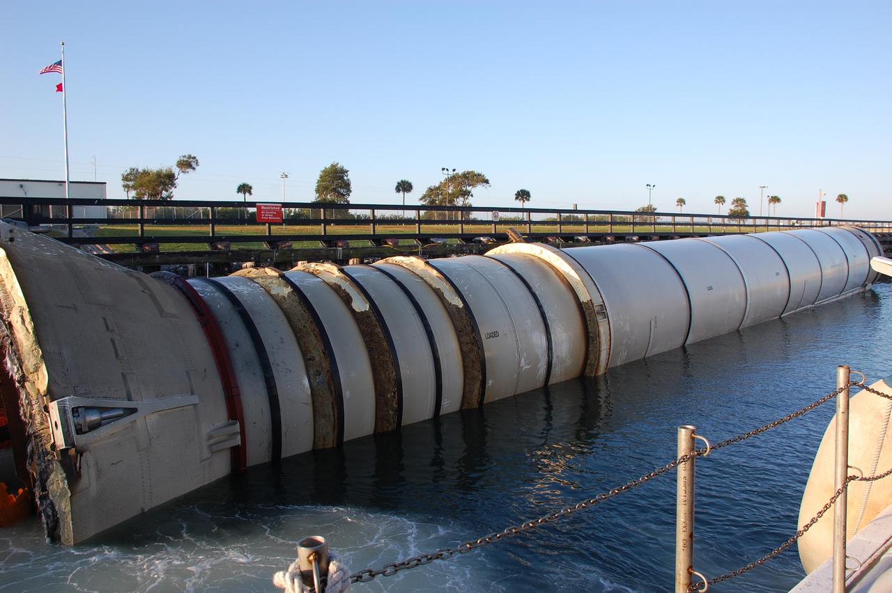 CAPE CANAVERAL, Fla. -- A spent shuttle booster will be ushered through the shallow waters of the locks at Port Canaveral, Fla., by a skiff from Freedom Star, one of NASA's solid rocket booster retrieval ships. The booster, which was used during space shuttle Discovery's STS-133 launch from NASA Kennedy Space Center's Launch Pad 39A on Feb. 24, is on its way to Hangar AF at Cape Canaveral Air Force Station. The shuttle’s two solid rocket booster casings and associated flight hardware are recovered in the Atlantic Ocean after every launch by Freedom Star and Liberty Star. The boosters impact the Atlantic about seven minutes after liftoff and the retrieval ships are stationed about 10 miles from the impact area at the time of splashdown.  After the spent segments are processed, they will be transported to Utah, where they will be refurbished and stored, if needed. Photo credit: NASA/Ben Smegelsky