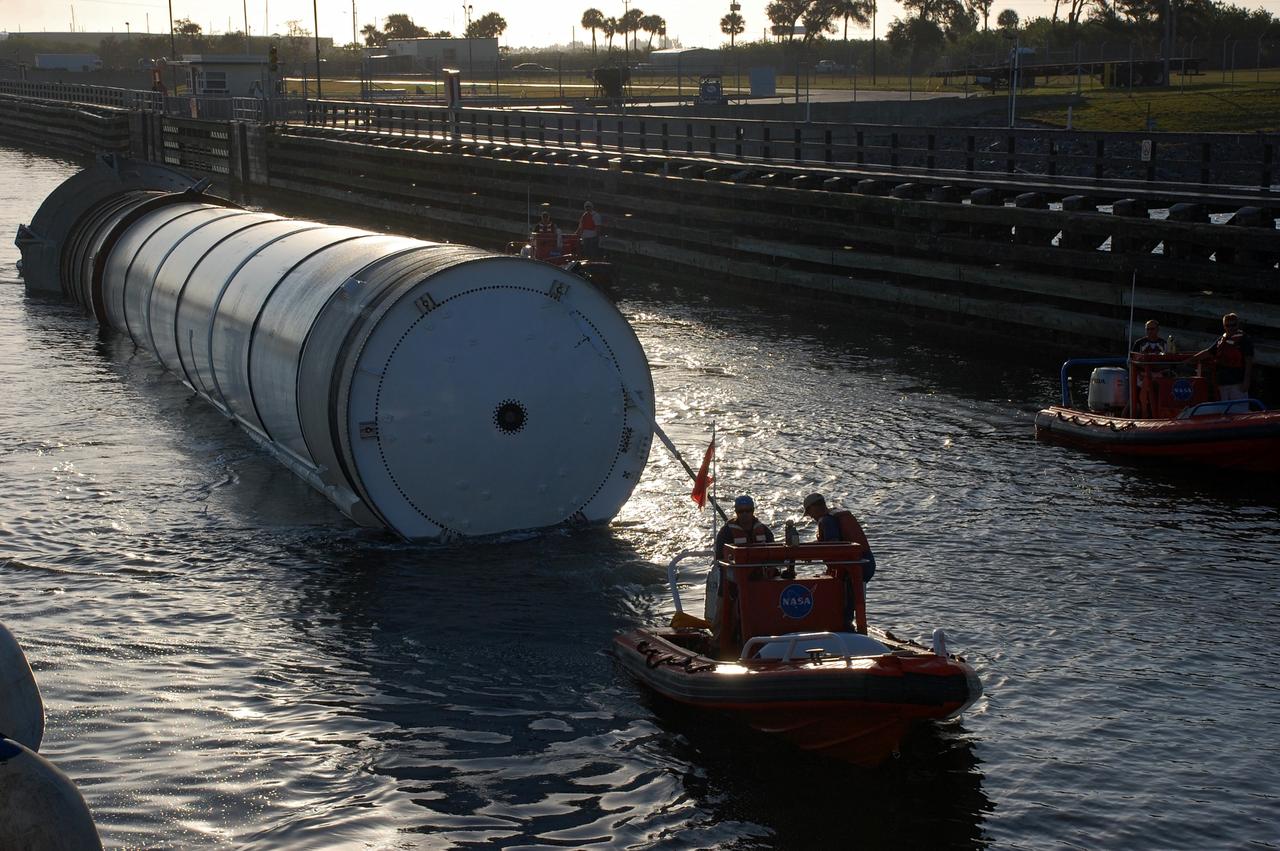 CAPE CANAVERAL, Fla. -- Crew members in a skiff from Freedom Star, one of NASA's solid rocket booster retrieval ships, usher a spent shuttle booster through the shallow waters of the locks at Port Canaveral, Fla. The booster, which was used during space shuttle Discovery's STS-133 launch from NASA Kennedy Space Center's Launch Pad 39A on Feb. 24, is on its way to Hangar AF at Cape Canaveral Air Force Station. The shuttle’s two solid rocket booster casings and associated flight hardware are recovered in the Atlantic Ocean after every launch by Freedom Star and Liberty Star. The boosters impact the Atlantic about seven minutes after liftoff and the retrieval ships are stationed about 10 miles from the impact area at the time of splashdown.  After the spent segments are processed, they will be transported to Utah, where they will be refurbished and stored, if needed. Photo credit: NASA/Ben Smegelsky