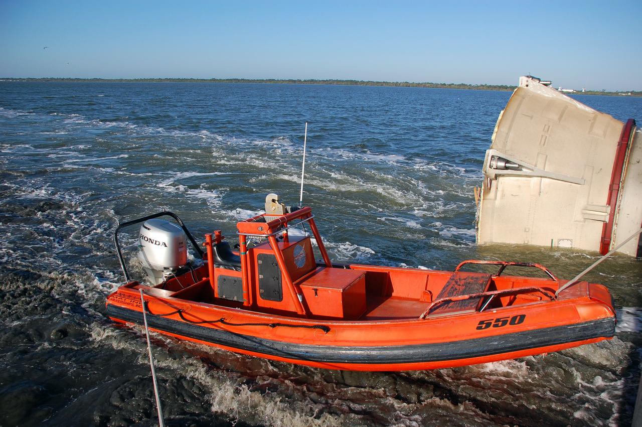 CAPE CANAVERAL, Fla. -- A skiff from Freedom Star, one of NASA's solid rocket booster retrieval ships, helped usher a spent shuttle booster through the shallow waters of the locks at Port Canaveral, Fla. The booster will be re-tied to the ship for the rest of the journey to Hangar AF at Cape Canaveral Air Force Station. The booster was used during space shuttle Discovery's STS-133 launch from NASA Kennedy Space Center's Launch Pad 39A on Feb. 24. The shuttle’s two solid rocket booster casings and associated flight hardware are recovered in the Atlantic Ocean after every launch by Freedom Star and Liberty Star. The boosters impact the Atlantic about seven minutes after liftoff and the retrieval ships are stationed about 10 miles from the impact area at the time of splashdown.  After the spent segments are processed, they will be transported to Utah, where they will be refurbished and stored, if needed. Photo credit: NASA/Ben Smegelsky