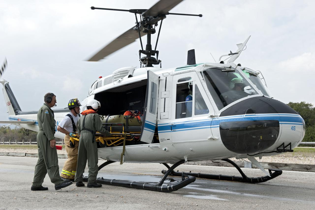 CAPE CANAVERAL, Fla. – Volunteers portraying injured astronauts are loaded onto a helicopter as part of an emergency exit, or Mode II/IV, exercise that allows teams to practice an emergency response at Launch Pad 39A at NASA's Kennedy Space Center in Florida. The exercise involves NASA fire rescue personnel, volunteers portraying astronauts with simulated injuries, helicopters and personnel from the Air Force’s 920th Rescue Wing, and medical trauma teams at three Central Florida hospitals. The drill allows teams to practice an emergency response at the launch pad, including helicopter evacuation to local hospitals.       Photo credit: NASA/Kim Shiflett