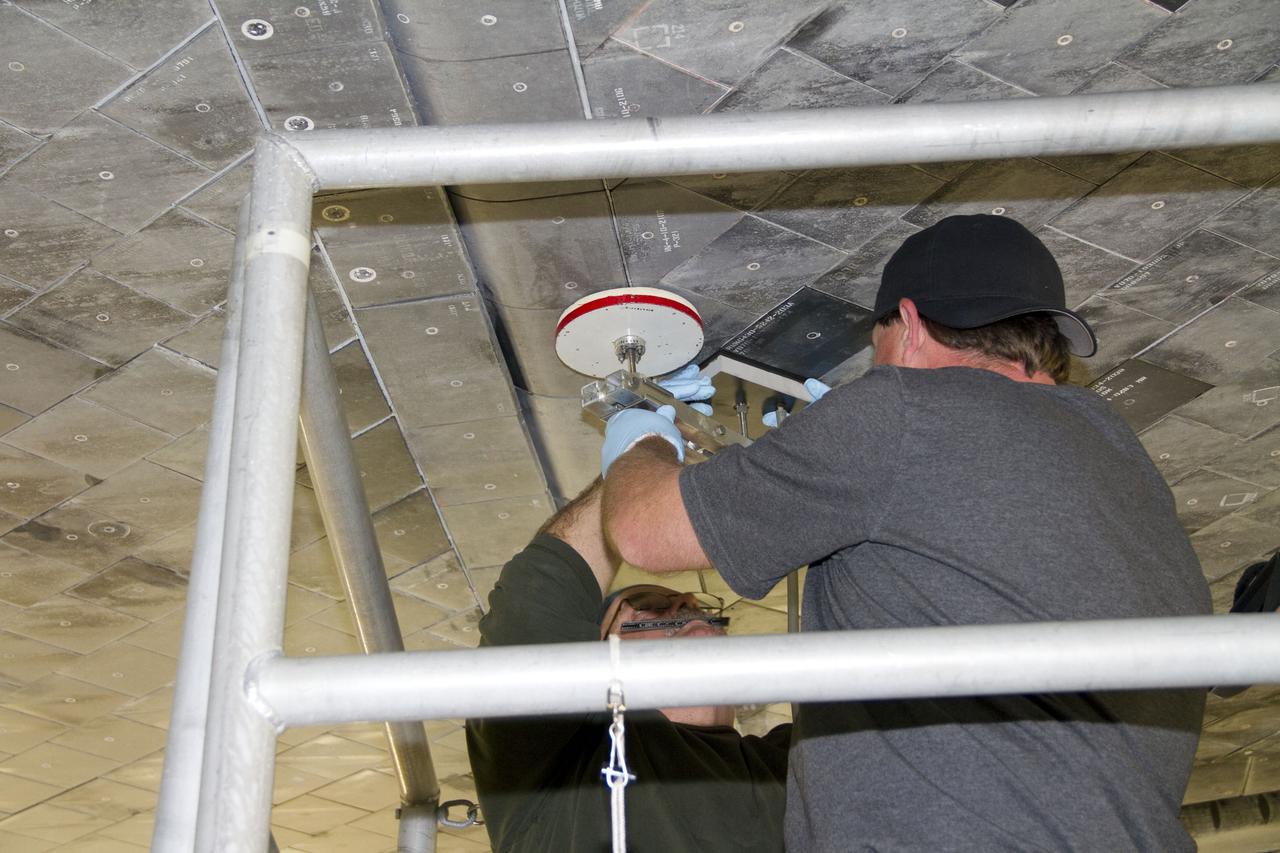 CAPE CANAVERAL, Fla. -- United Space Alliance technicians perform a pull test on shuttle Atlantis' thermal protection tiles in Orbiter Processing Facility-1 at NASA's Kennedy Space Center in Florida. The pull test measures the force it takes to pull a tile off of the shuttle in order to make sure the bond between the two is strong enough to withstand the force of launch and landing. Atlantis is being prepared for the STS-135 mission, which will deliver the Raffaello multipurpose logistics module packed with supplies, logistics and spare parts to the International Space Station. STS-135 is targeted to launch June 28, and will be the last spaceflight for the Space Shuttle Program. Photo credit: NASA/Jack Pfaller