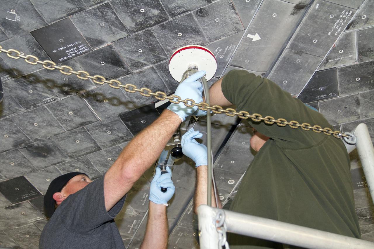 CAPE CANAVERAL, Fla. -- United Space Alliance technicians perform a pull test on shuttle Atlantis' thermal protection tiles in Orbiter Processing Facility-1 at NASA's Kennedy Space Center in Florida. The pull test measures the force it takes to pull a tile off of the shuttle in order to make sure the bond between the two is strong enough to withstand the force of launch and landing. Atlantis is being prepared for the STS-135 mission, which will deliver the Raffaello multipurpose logistics module packed with supplies, logistics and spare parts to the International Space Station. STS-135 is targeted to launch June 28, and will be the last spaceflight for the Space Shuttle Program. Photo credit: NASA/Jack Pfaller