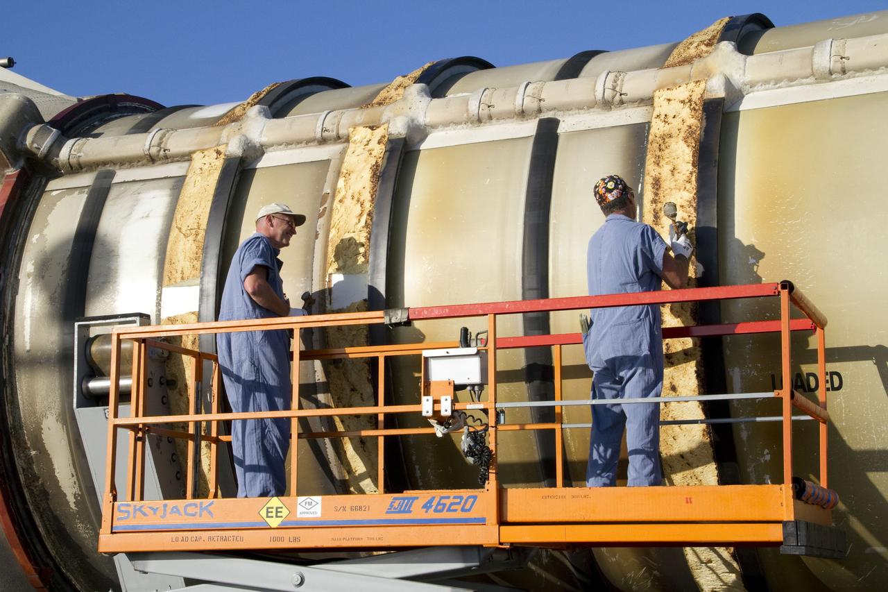 CAPE CANAVERAL, Fla. -- Technicians inspect a spent shuttle solid rocket booster outside Hangar AF at Cape Canaveral Air Force Station in Florida. The booster was used during space shuttle Discovery's STS-133 launch from NASA Kennedy Space Center's Launch Pad 39A on Feb. 24. The shuttle’s two solid rocket booster casings and associated flight hardware were recovered in the Atlantic Ocean by retrieval ships Liberty Star and Freedom Star. The boosters impact the Atlantic about seven minutes after liftoff and the retrieval ships are stationed about 10 miles from the impact area at the time of splashdown. After the spent segments are processed, they will be transported to Utah, where they will be refurbished and stored, if needed. Photo credit: NASA/Jack Pfaller