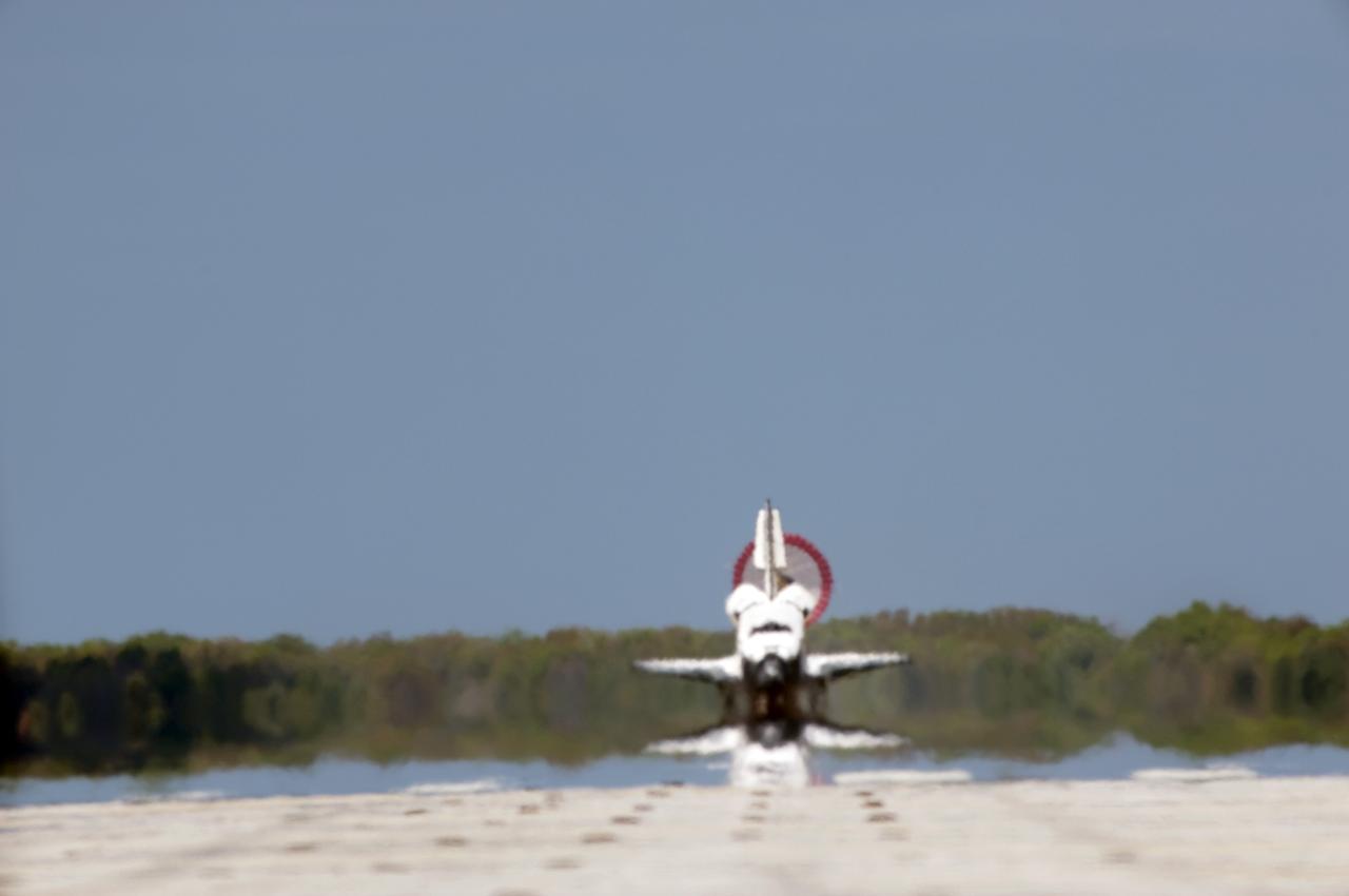 CAPE CANAVERAL, Fla. - Space shuttle Discovery, its drag chute unfurled, appears to be a mirage as it travels down Runway 15 at the Shuttle Landing Facility at NASA's Kennedy Space Center in Florida. Discovery's final return from space completed the 13-day, 5.3-million-mile STS-133 mission. Main gear touchdown was at 11:57:17 a.m., followed by nose gear touchdown at 11:57:28, and wheelstop at 11:58:14 a.m. On board are Commander Steve Lindsey, Pilot Eric Boe, and Mission Specialists Nicole Stott, Michael Barratt, Alvin Drew and Steve Bowen. Discovery and its six-member crew delivered the Permanent Multipurpose Module, packed with supplies and critical spare parts, as well as Robonaut 2, the dexterous humanoid astronaut helper, to the orbiting outpost. STS-133 was Discovery's 39th and final mission. This was the 133rd Space Shuttle Program mission and the 35th shuttle voyage to the space station. Photo credit: NASA/Tony Gray and Tom Farrar