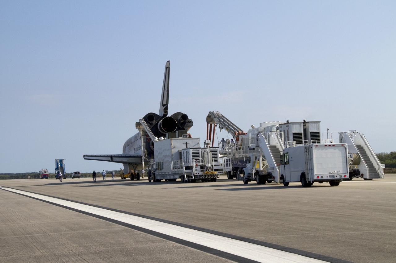 CAPE CANAVERAL, Fla. - Vehicles in the landing convoy surround space shuttle Discovery at NASA's Kennedy Space Center in Florida.  A purge unit, connected to Discovery's aft end, pumps conditioned air into the shuttle for the slow trip from the Shuttle Landing Facility to Orbiter Processing Facility-2. Discovery touched down on Runway 15 at 11:57 a.m., bringing an end to its 39th and final spaceflight mission, STS-133. Discovery and its six-member STS-133 crew delivered the Permanent Multipurpose Module, packed with supplies and critical spare parts, as well as Robonaut 2, the dexterous humanoid astronaut helper, to the International Space Station.    Inside the processing facility, Discovery will be prepared for future public display.  Photo credit: NASA/Jack Pfaller