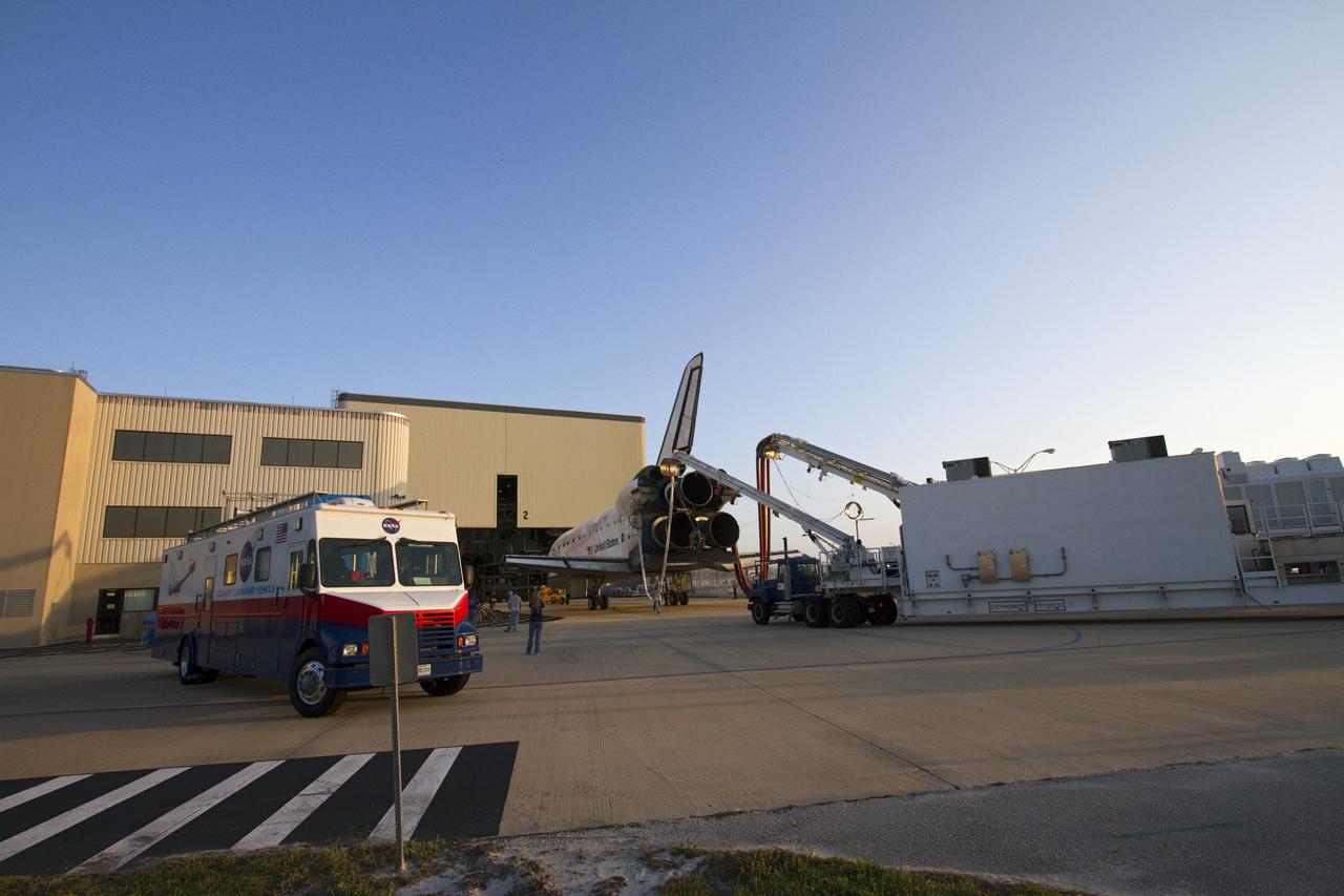 CAPE CANAVERAL, Fla. - The Convoy Command Vehicle moves aside while space shuttle Discovery is positioned outside the door of Orbiter Processing Facility-2 at NASA's Kennedy Space Center in Florida.  Discovery is attached to a purge unit that pumps conditioned air into the shuttle while it is towed. Discovery touched down on the Shuttle Landing Facility's Runway 15 at 11:57 a.m., bringing an end to its 39th and final spaceflight mission, STS-133. Discovery and its six-member STS-133 crew delivered the Permanent Multipurpose Module, packed with supplies and critical spare parts, as well as Robonaut 2, the dexterous humanoid astronaut helper, to the International Space Station.    Inside the processing facility, Discovery will be prepared for future public display.  Photo credit: NASA/Jack Pfaller