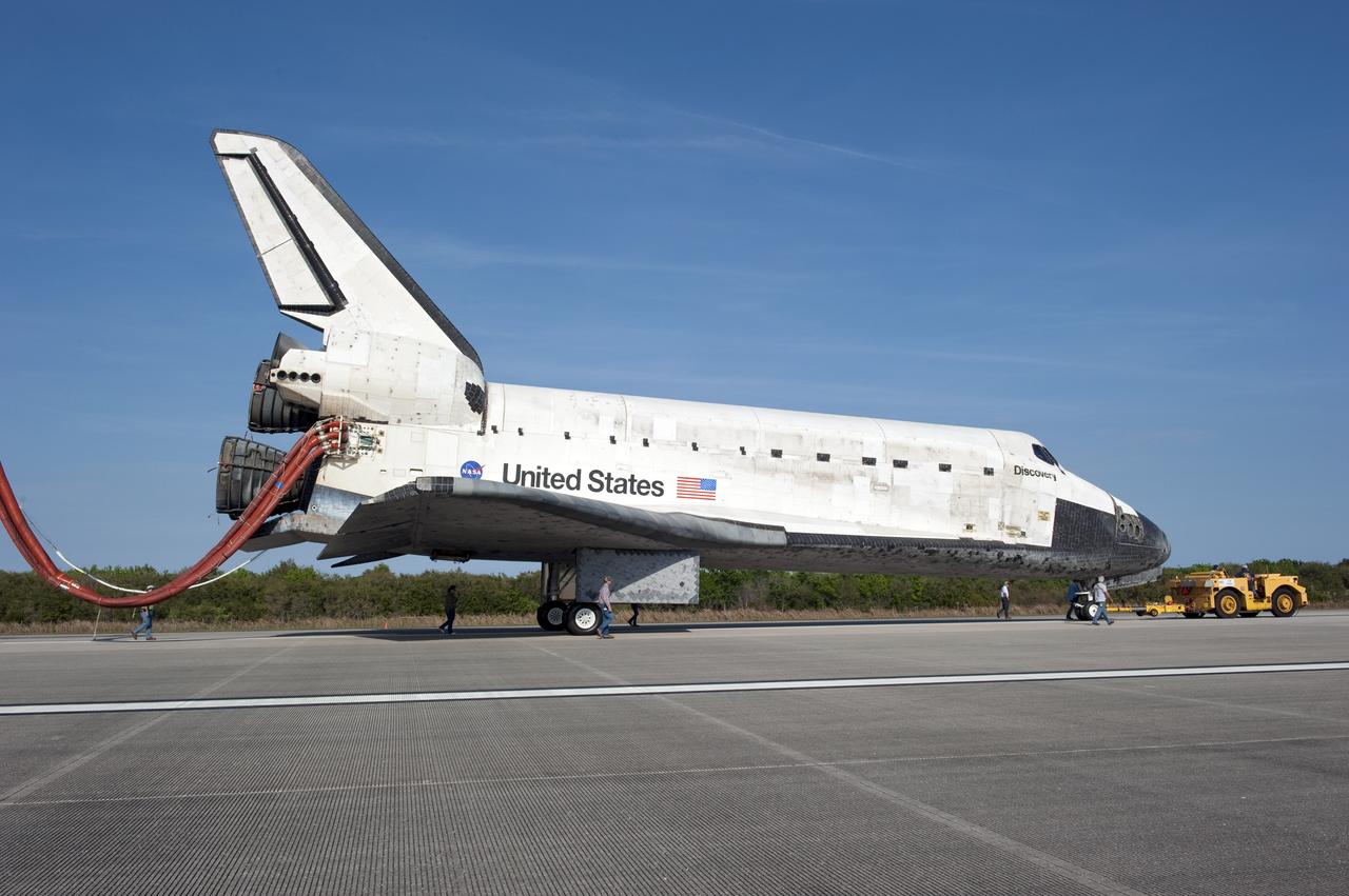 CAPE CANAVERAL, Fla. - The "towback" vehicle slowly pulls Space shuttle Discovery from the Shuttle Landing Facility to Orbiter Processing Facility-2 at NASA's Kennedy Space Center in Florida. Discovery touched down on Runway 15 at 11:57 a.m., bringing an end to its 39th and final spaceflight mission, STS-133. Discovery and its six-member STS-133 crew delivered the Permanent Multipurpose Module, packed with supplies and critical spare parts, as well as Robonaut 2, the dexterous humanoid astronaut helper, to the International Space Station.    Inside the processing facility, Discovery will be prepared for future public display.  Photo credit: NASA/Kim Shiflett