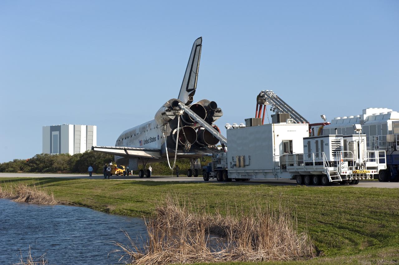 CAPE CANAVERAL, Fla. - Space shuttle Discovery, attached to a purge unit that pumps conditioned air into the shuttle while it is towed, rolls along the towway from the Shuttle Landing Facility to Orbiter Processing Facility-2 at NASA's Kennedy Space Center in Florida. In the distance at left is the 525-foot-tall Vehicle Assembly Building. Discovery touched down on Runway 15 at 11:57 a.m., bringing an end to its 39th and final spaceflight mission, STS-133. Discovery and its six-member STS-133 crew delivered the Permanent Multipurpose Module, packed with supplies and critical spare parts, as well as Robonaut 2, the dexterous humanoid astronaut helper, to the International Space Station. Inside the processing facility, Discovery will be prepared for future public display. Photo credit: NASA/Kim Shiflett