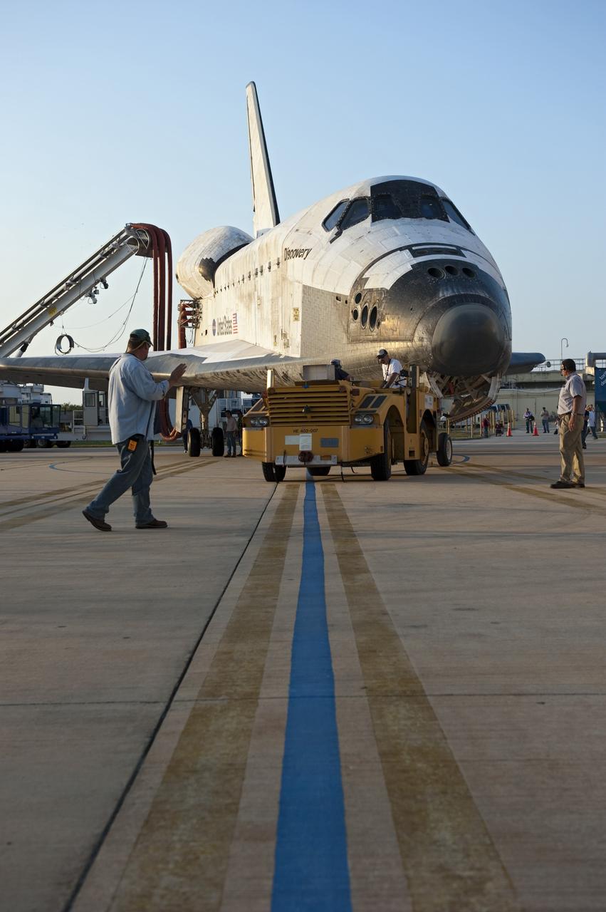 CAPE CANAVERAL, Fla. - Employees guide space shuttle Discovery into position for entry into Orbiter Processing Facility-2 at NASA's Kennedy Space Center in Florida. Discovery touched down on the Shuttle Landing Facility's Runway 15 at 11:57 a.m., bringing an end to its 39th and final spaceflight mission, STS-133. Discovery and its six-member STS-133 crew delivered the Permanent Multipurpose Module, packed with supplies and critical spare parts, as well as Robonaut 2, the dexterous humanoid astronaut helper, to the International Space Station.    Inside the processing facility, Discovery will be prepared for future public display.  Photo credit: NASA/Kim Shiflett