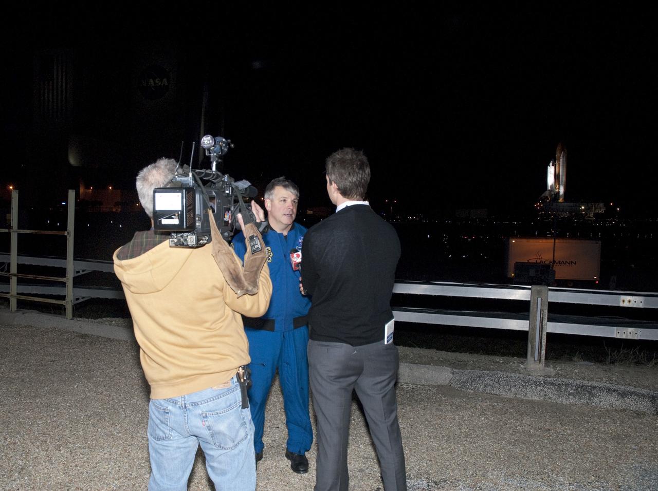 CAPE CANAVERAL, Fla. -- STS-134 Pilot Greg H. Johnson talks to media as the space shuttle that will take Johnson and his crewmates to the International Space Station slowly rolls past. Endeavour began its move from High Bay 3 in the Vehicle Assembly Building to Launch Pad 39A at NASA's Kennedy Space Center in Florida at 7:56 p.m. EST. The 3.4-mile trek, known as "rollout," will take about seven hours to complete. This is the final scheduled rollout for Endeavour, which is attached to its external fuel tank and solid rocket boosters atop a crawler-transporter. STS-134 crew members will deliver the Express Logistics Carrier-3, Alpha Magnetic Spectrometer-2 (AMS), a high-pressure gas tank, additional spare parts for the Dextre robotic helper and micrometeoroid debris shields to the orbiting outpost on the shuttle's final spaceflight. Launch is targeted for April 19 at 7:48 p.m. EDT. For more information visit, www.nasa.gov/mission_pages/shuttle/shuttlemissions/sts134/index.html. Photo credit: NASA/Debbie Odom
