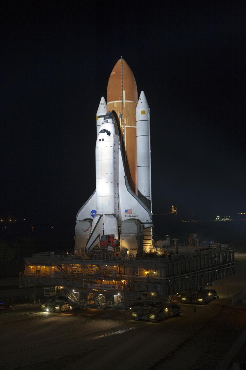 CAPE CANAVERAL, Fla. -- Bathed in xenon lights, space shuttle Endeavour begins its nighttime journey from the Vehicle Assembly Building to Launch Pad 39A, illuminated in the background, at NASA's Kennedy Space Center in Florida.     Riding atop a crawler-transporter attached to its external fuel tank and solid rocket boosters, Endeavour's 3.4-mile trek, known as "rollout," began at 7:56 p.m. EST and will take about seven hours to complete. This is the final scheduled rollout for Endeavour.  Endeavour and its six-member crew will deliver the Express Logistics Carrier-3, Alpha Magnetic Spectrometer-2 (AMS), a high-pressure gas tank, additional spare parts for the Dextre robotic helper and micrometeoroid debris shields to the International Space Station on the shuttle's final spaceflight, STS-134. Launch is targeted for 7:48 p.m. EDT April 19. For more information, visit www.nasa.gov/mission_pages/shuttle/shuttlemissions/sts134/index.html. Photo credit: NASA/Terry Zaperach