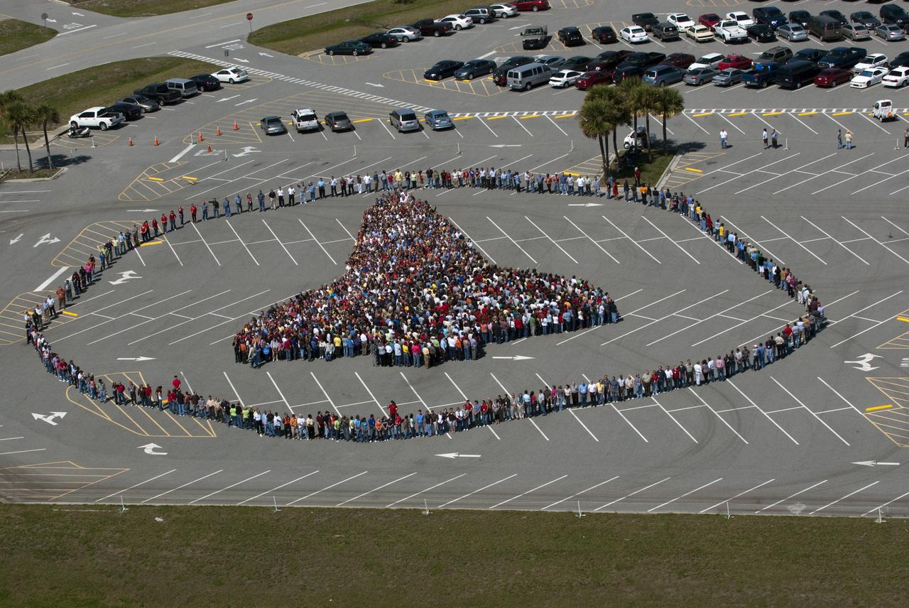 CAPE CANAVERAL, Fla. -- Thousands of NASA Kennedy Space Center employees stand side-by-side to form a full-scale outline of a space shuttle orbiter outside the Vehicle Assembly Building. The unique photo opportunity was designed to honor the Space Shuttle Program's 30-year legacy and the people who contribute to safely processing, launching and landing the vehicle.        To learn more about the space shuttle era, including videos, photos and feature stories, go to www.nasa.gov/mission_pages/shuttle/flyout/index.html. Photo credit: NASA/Kim Shiflett