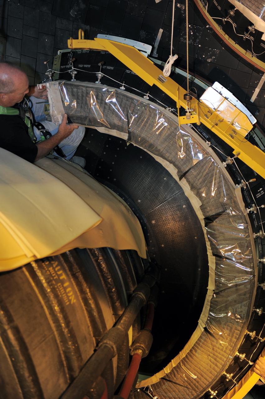 CAPE CANAVERAL, Fla. - Crews in Orbiter Processing Facility-2 at NASA's Kennedy Space Center in Florida remove space shuttle Discovery's right-hand inner heat shield from engine No. 1. The removal is part of Discovery's transition and retirement processing. Work performed on Discovery is expected to help rocket designers build next-generation spacecraft and prepare the shuttle for future public display.Photo credit: NASA/Kim Shiflett