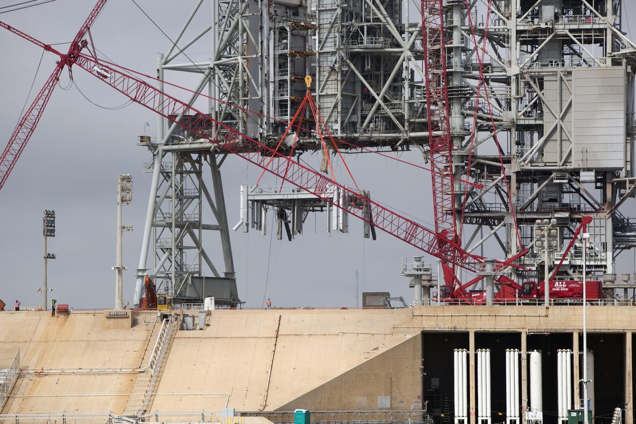 Cape Canaveral, Fla. -- A large crane dismantles the next section of the fixed service structure (FSS) on Launch Pad 39B at NASA's Kennedy Space Center in Florida. Work to remove the rotating service structure (RSS) also continues at the pad. The FSS and RSS were designed to support the unique needs of the Space Shuttle Program. In 2009, the pad was no longer needed for the shuttle program, so it is being restructured for future use. Its new design will feature a "clean pad" for rockets to come with their own launcher, making it more versatile for a number of vehicles. The new lightning protection system, which was in place for the October 2009 launch of Ares I-X, will remain. For information on NASA's future plans, visit www.nasa.gov. Photo credit: NASA/Dimitri Gerondidakis