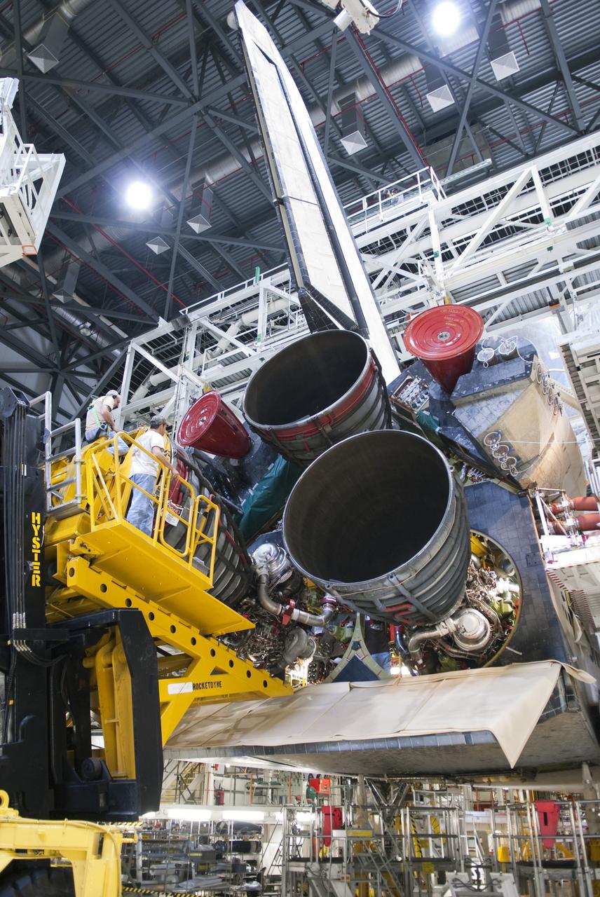 CAPE CANAVERAL, Fla. -- A main engine slowly emerges from space shuttle Discovery. The work is taking place in Orbiter Processing Facility-2 at NASA's Kennedy Space Center in Florida. The transition and retirement processing is expected to help rocket designers build next-generation spacecraft and prepare the shuttle for display. Photo credit: NASA/Jim Grossmann