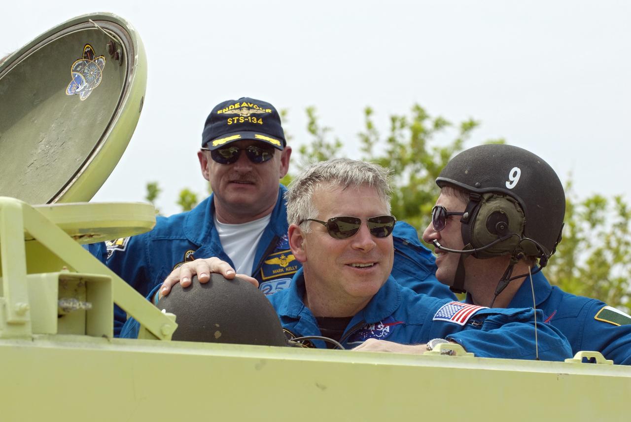 CAPE CANAVERAL, Fla. - STS-134 Pilot Greg H. Johnson takes time out from driving practice of the M113 armored personnel carrier to pose for a photo at NASA's Kennedy Space Center in Florida. With Johnson is Commander Mark Kelly (left) and European Space Agency astronaut Roberto Vittori. An M113 is kept at the foot of the launch pad in case an emergency exit from the pad is needed and every shuttle crew is trained on driving the vehicle before launch. Space shuttle Endeavour's six crew members are at Kennedy for the launch countdown dress rehearsal called the Terminal Countdown Demonstration Test (TCDT) and related training. Targeted to launch April 19 at 7:48 p.m. EDT, they will deliver the Express Logistics Carrier-3, Alpha Magnetic Spectrometer-2 (AMS), a high-pressure gas tank, additional spare parts for the Dextre robotic helper and micrometeoroid debris shields to the space station. This is the final scheduled spaceflight for Endeavour. For more information visit, www.nasa.gov/mission_pages/shuttle/shuttlemissions/sts134/index.html. Photo credit: NASA/Kim Shiflett