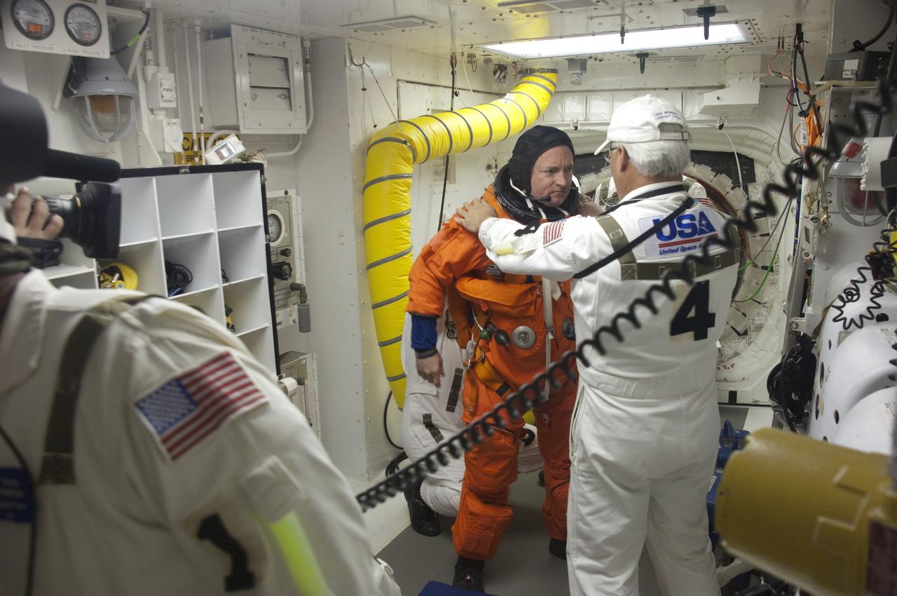 CAPE CANAVERAL, Fla. -- In the White Room of Launch Pad 39A at NASA's Kennedy Space Center in Florida, the Closeout Crew helps STS-134 Commander Mark Kelly put on the parachute for his launch-and-entry suit before he boards space shuttle Endeavour during the Terminal Countdown Demonstration Test (TCDT). Part of TCDT includes practicing the final hours of a real launch day when astronauts put on their launch-and-entry suits, ride to the pad in the Astrovan and strap into the shuttle.    Endeavour's six crew members are targeted to launch April 19 at 7:48 p.m. EDT. They will deliver the Express Logistics Carrier-3, Alpha Magnetic Spectrometer-2 (AMS), a high-pressure gas tank, additional spare parts for the Dextre robotic helper and micrometeoroid debris shields to the International Space Station. This will be the final spaceflight for Endeavour. For more information visit, www.nasa.gov/mission_pages/shuttle/shuttlemissions/sts134/index.html. Photo credit: NASA/Kevin O'Connell