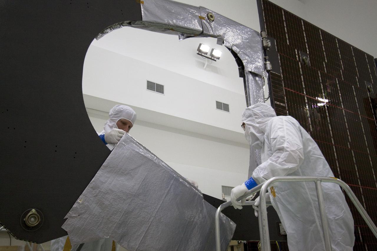 CAPE CANAVERAL, Fla. -- Technicians in the Astrotech payload processing facility in Titusville, Fla., begin installing insulating blankets around the magnetometer boom. The boom structure is attached to Juno's solar array #1 that will help power the NASA spacecraft on its mission to Jupiter.          Juno is scheduled to launch aboard an Atlas V rocket from Cape Canaveral, Fla., on Aug. 5, 2011, reaching Jupiter in July 2016. The spacecraft will orbit the giant planet more than 30 times, skimming to within 3,000 miles above its cloud tops, for about one year. With its suite of science instruments, the spacecraft will investigate the existence of a solid planetary core, map Jupiter's intense magnetic field, measure the amount of water and ammonia in the deep atmosphere, and observe the planet's auroras. For more information visit, www.nasa.gov/juno. Photo credit: NASA/Jack Pfaller