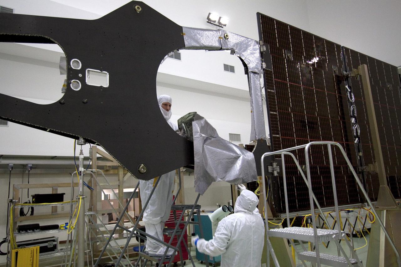 CAPE CANAVERAL, Fla. -- Technicians in the Astrotech payload processing facility in Titusville, Fla., begin installing insulating blankets around the magnetometer boom. The boom structure is attached to Juno's solar array #1 that will help power the NASA spacecraft on its mission to Jupiter.          Juno is scheduled to launch aboard an Atlas V rocket from Cape Canaveral, Fla., on Aug. 5, 2011, reaching Jupiter in July 2016. The spacecraft will orbit the giant planet more than 30 times, skimming to within 3,000 miles above its cloud tops, for about one year. With its suite of science instruments, the spacecraft will investigate the existence of a solid planetary core, map Jupiter's intense magnetic field, measure the amount of water and ammonia in the deep atmosphere, and observe the planet's auroras. For more information visit, www.nasa.gov/juno. Photo credit: NASA/Jack Pfaller