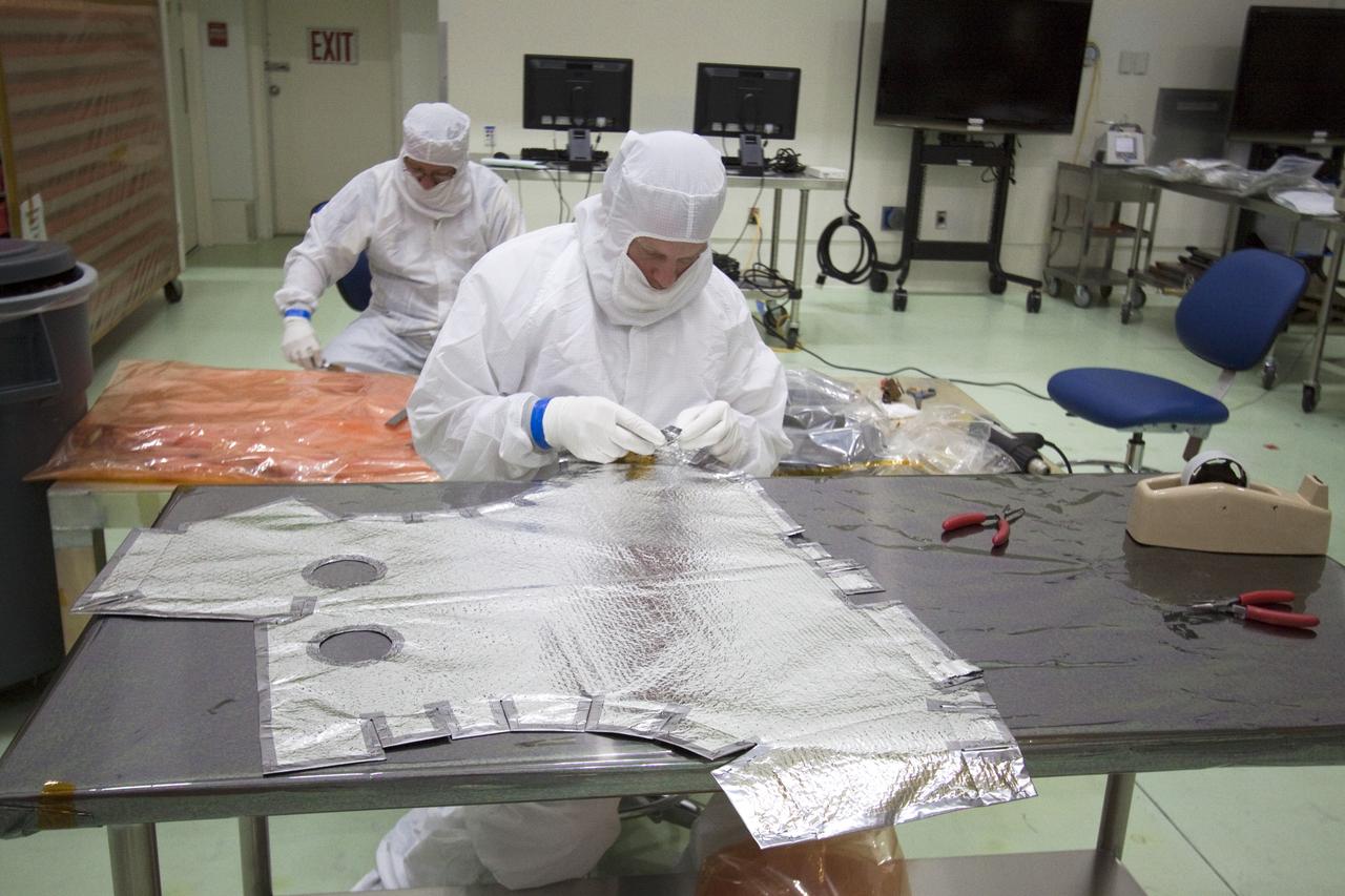 CAPE CANAVERAL, Fla. -- A technician in the Astrotech payload processing facility in Titusville, Fla., inspects one of the insulating blanket sections that will be installed on the magnetometer boom. The boom structure is attached to Juno's solar array #1 that will help power the NASA spacecraft on its mission to Jupiter.      Juno is scheduled to launch aboard an Atlas V rocket from Cape Canaveral, Fla., on Aug. 5, 2011, reaching Jupiter in July 2016. The spacecraft will orbit the giant planet more than 30 times, skimming to within 3,000 miles above its cloud tops, for about one year. With its suite of science instruments, the spacecraft will investigate the existence of a solid planetary core, map Jupiter's intense magnetic field, measure the amount of water and ammonia in the deep atmosphere, and observe the planet's auroras. For more information visit, www.nasa.gov/juno. Photo credit: NASA/Jack Pfaller