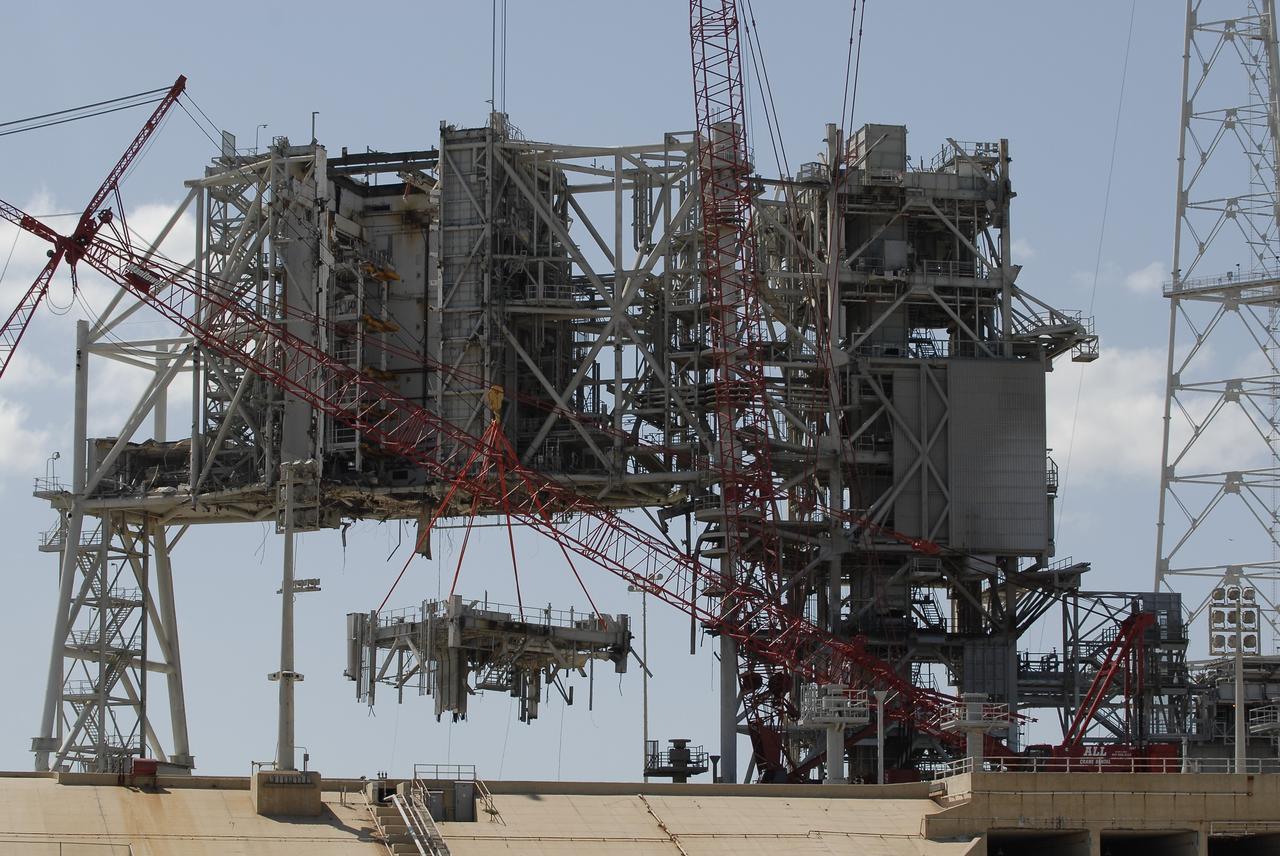 Cape Canaveral, Fla. -- A large crane dismantles another section of the fixed service structure (FSS) on Launch Pad 39B at NASA's Kennedy Space Center in Florida. Work to remove the rotating service structure (RSS) also continues at the pad. The FSS and RSS were designed to support the unique needs of the Space Shuttle Program. In 2009, the pad was no longer needed for the shuttle program, so it is being restructured for future use. Its new design will feature a "clean pad" for rockets to come with their own launcher, making it more versatile for a number of vehicles. The new lightning protection system, which was in place for the October 2009 launch of Ares I-X, will remain. For information on NASA's future plans, visit www.nasa.gov. Photo credit: NASA/Kim Shiflett