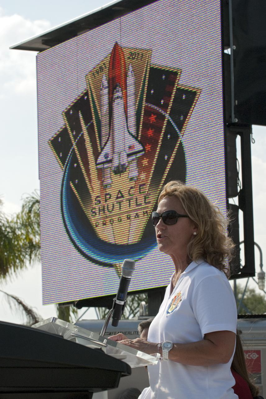 CAPE CANAVERAL, Fla. -- Standing under the insignia designed for the Space Shuttle Program, Patty Stratton, associate program manager for Ground Operations at United Space Alliance, speaks to the audience attending a 30th anniversary celebration in honor of the Space Shuttle Program's first shuttle launch at NASA's Kennedy Space Center Visitor Complex in Florida. The celebration followed an announcement by NASA Administrator Charles Bolden where the four orbiters will be placed for permanent display after retirement. Photo credit: NASA/Kim Shiflett