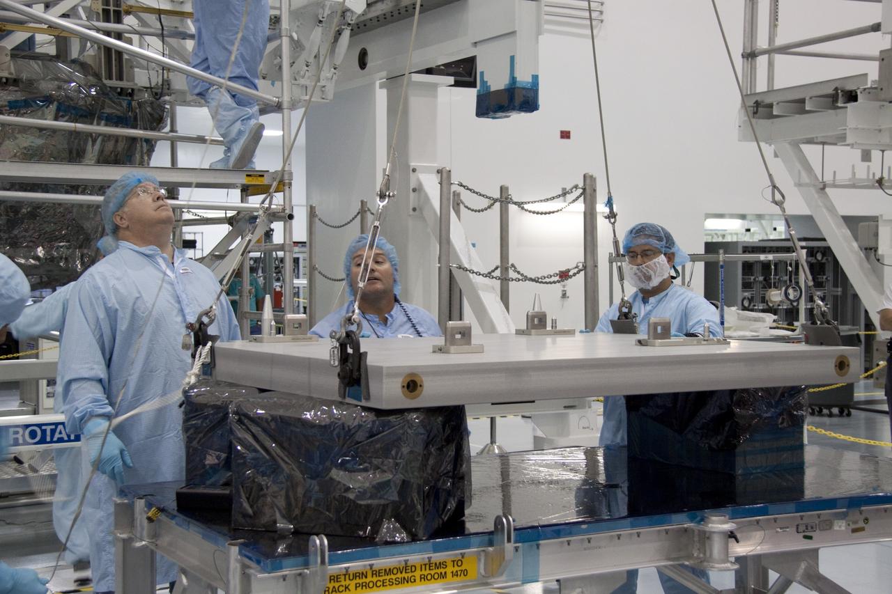 CAPE CANAVERAL, Fla. - In the Space Station Processing Facility at NASA's Kennedy Space Center in Florida, technicians monitor the progress of an overhead crane as it lifts the pump module assembly plate for transfer to the Lightweight Multi-Purpose Experiment Support Structure Carrier, or LMC. The module assembly will be used to secure the return of a failed ammonia pump module in shuttle Atlantis' payload bay. Atlantis and its payload are being prepared for the STS-135 mission, which will deliver the Raffaello multipurpose logistics module packed with supplies, logistics and spare parts to the International Space Station. STS-135 is targeted to launch June 28, and will be the last spaceflight for the Space Shuttle Program. Photo credit: NASA/Jack Pfaller