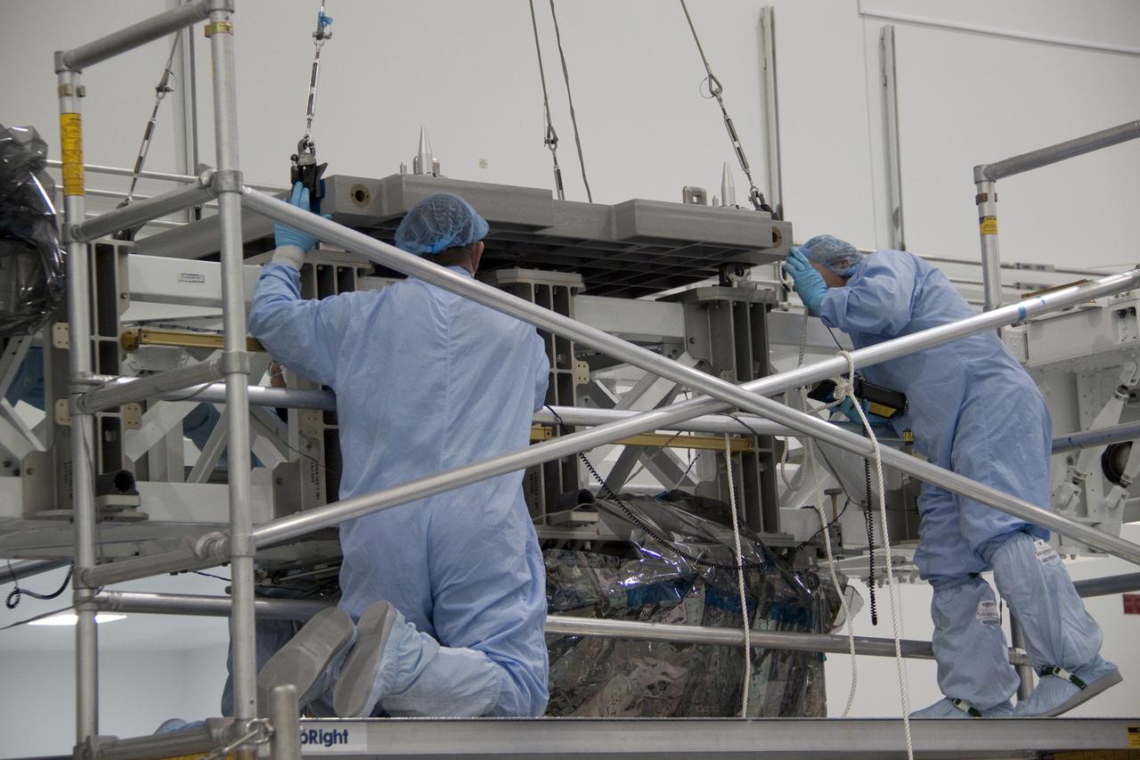 CAPE CANAVERAL, Fla. - In the Space Station Processing Facility at NASA's Kennedy Space Center in Florida, technicians guide an overhead crane as it lowers the pump module assembly plate toward the Lightweight Multi-Purpose Experiment Support Structure Carrier, or LMC. The module assembly will be used to secure the return of a failed ammonia pump module in shuttle Atlantis' payload bay. Atlantis and its payload are being prepared for the STS-135 mission, which will deliver the Raffaello multipurpose logistics module packed with supplies, logistics and spare parts to the International Space Station. STS-135 is targeted to launch June 28, and will be the last spaceflight for the Space Shuttle Program. Photo credit: NASA/Jack Pfaller