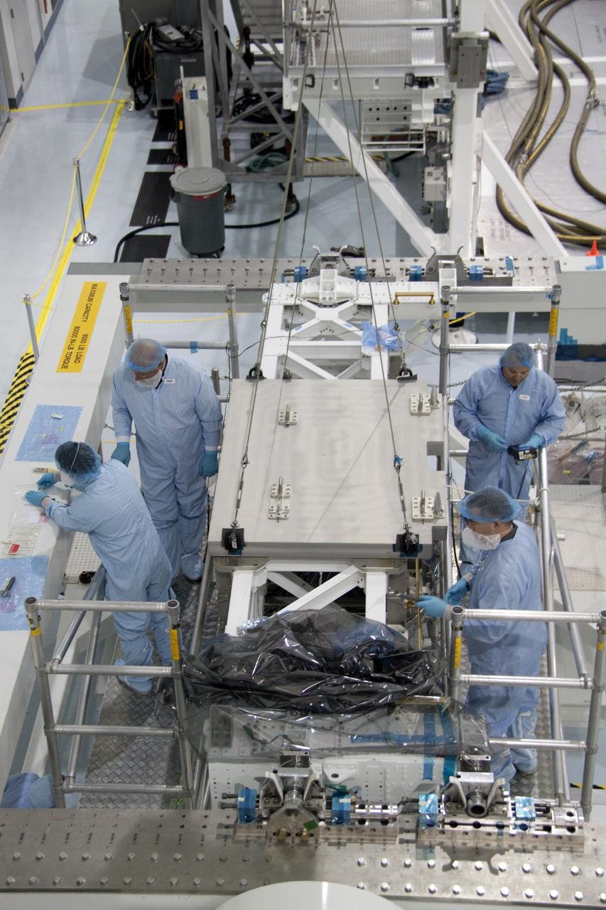 CAPE CANAVERAL, Fla. - In the Space Station Processing Facility at NASA's Kennedy Space Center in Florida, technicians secure the pump module assembly plate into position onto the Lightweight Multi-Purpose Experiment Support Structure Carrier, or LMC. The module assembly will be used to secure the return of a failed ammonia pump module in shuttle Atlantis' payload bay. Atlantis and its payload are being prepared for the STS-135 mission, which will deliver the Raffaello multipurpose logistics module packed with supplies, logistics and spare parts to the International Space Station. STS-135 is targeted to launch June 28, and will be the last spaceflight for the Space Shuttle Program. Photo credit: NASA/Jack Pfaller
