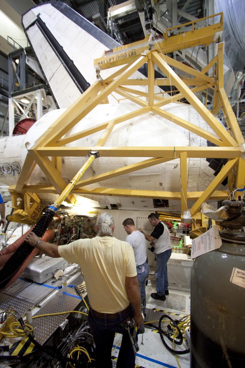CAPE CANAVERAL, Fla. - In Orbiter Processing Facility-2 at NASA's Kennedy Space Center in Florida, workers prepare to remove shuttle Discovery's right-hand orbital maneuvering system, or OMS, pod. The removal is part of Discovery's transition and retirement processing. Work performed on Discovery is expected to help rocket designers build next-generation spacecraft and prepare the shuttle for future public display. Photo credit: NASA/Troy Cryder
