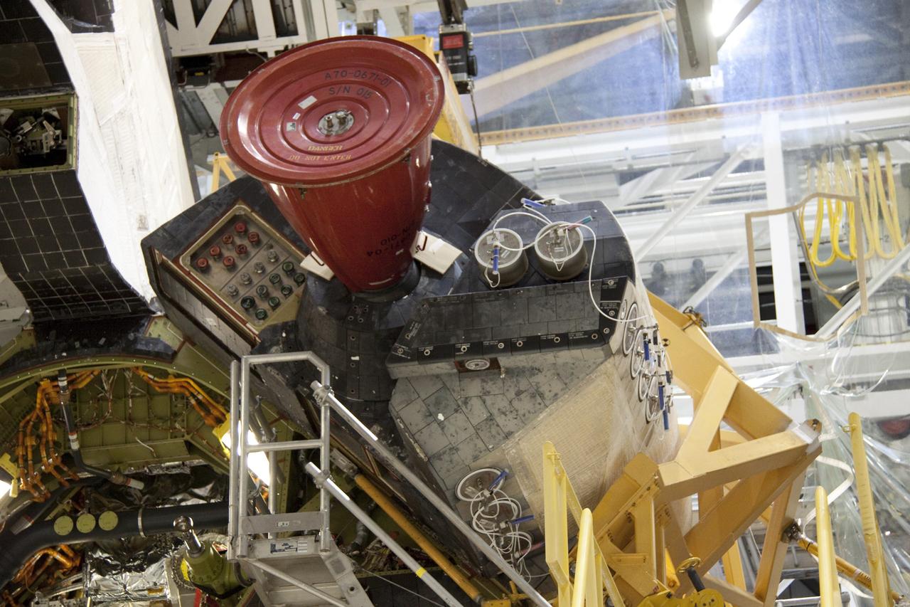 CAPE CANAVERAL, Fla. -- In Orbiter Processing Facility-2 at NASA's Kennedy Space Center in Florida, workers remove shuttle Discovery's right-hand orbital maneuvering system, or OMS, pod. The removal is part of Discovery's transition and retirement processing. Work performed on Discovery is expected to help rocket designers build next-generation spacecraft and prepare the shuttle for future public display. Photo credit: NASA/Troy Cryder