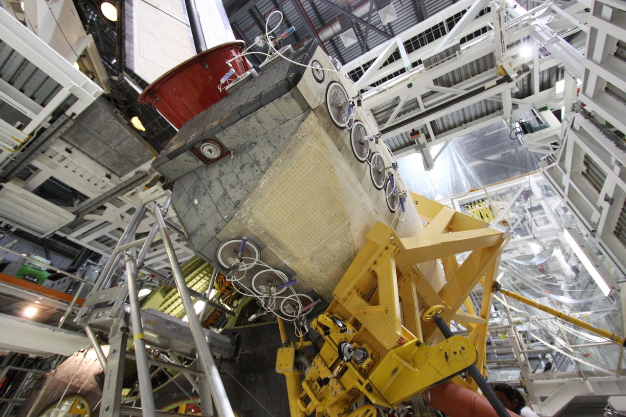CAPE CANAVERAL, Fla. - In Orbiter Processing Facility-2 at NASA's Kennedy Space Center in Florida, workers use a crane to grapple shuttle Discovery's right-hand orbital maneuvering system, or OMS, pod for removal. It then will be transported to the Hypergol Maintenance Facility. The removal is part of Discovery's transition and retirement processing. Work performed on Discovery is expected to help rocket designers build next-generation spacecraft and prepare the shuttle for future public display. Photo credit: NASA/Troy Cryder