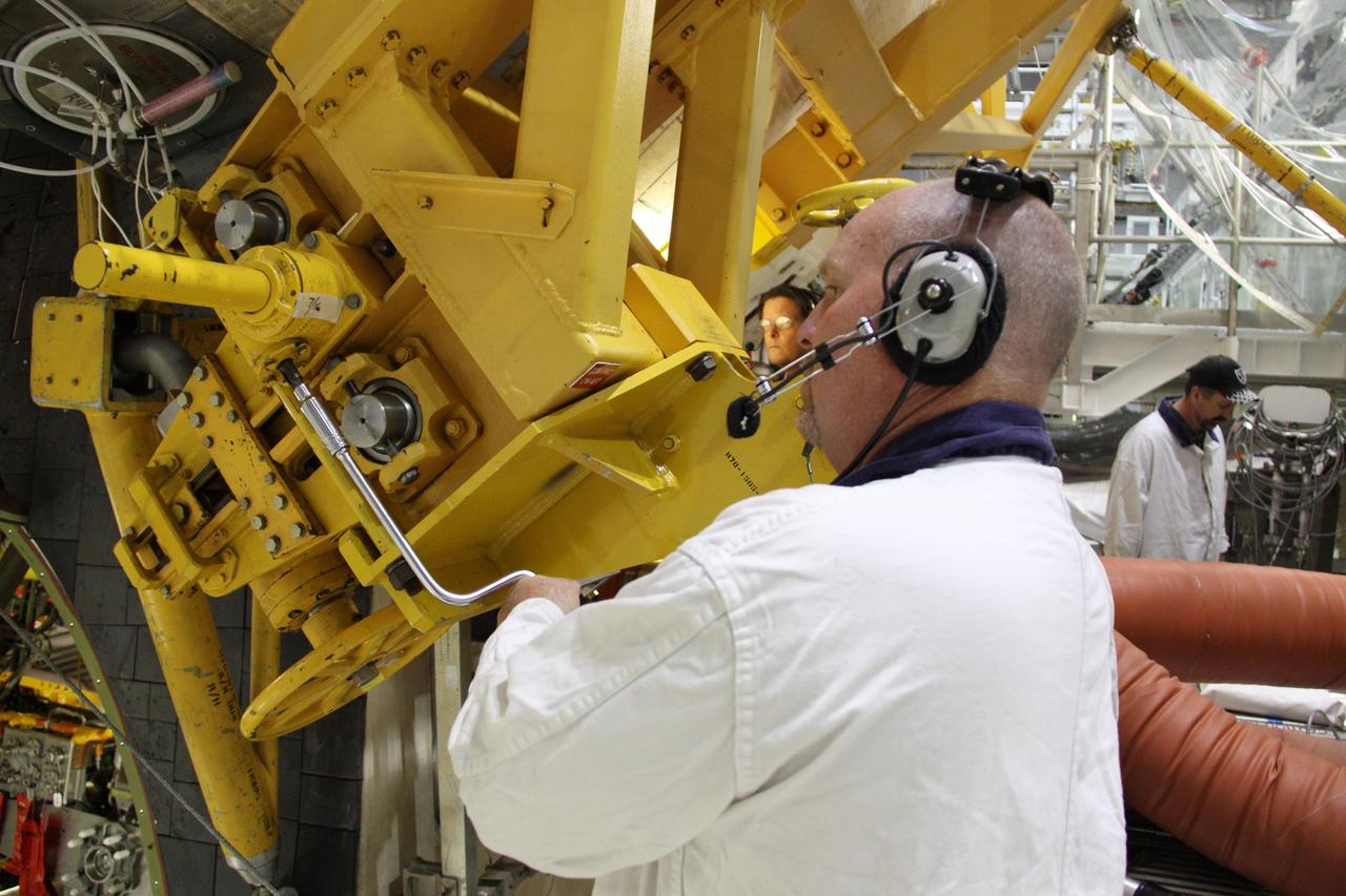 CAPE CANAVERAL, Fla. - In Orbiter Processing Facility-2 at NASA's Kennedy Space Center in Florida, workers use a crane to grapple shuttle Discovery's right-hand orbital maneuvering system, or OMS, pod for removal. It then will be transported to the Hypergol Maintenance Facility. The removal is part of Discovery's transition and retirement processing. Work performed on Discovery is expected to help rocket designers build next-generation spacecraft and prepare the shuttle for future public display. Photo credit: NASA/Troy Cryder