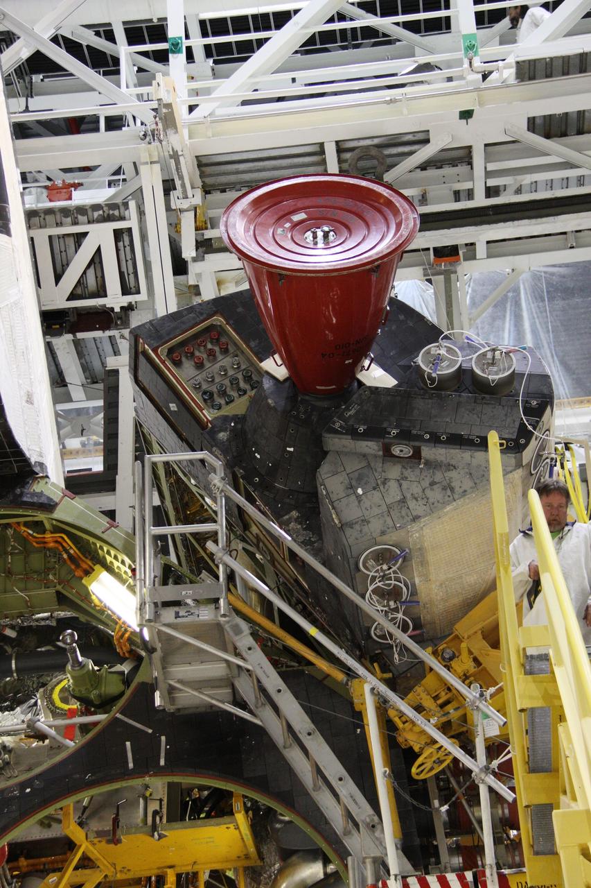 CAPE CANAVERAL, Fla. - In Orbiter Processing Facility-2 at NASA's Kennedy Space Center in Florida, workers use a crane to grapple shuttle Discovery's right-hand orbital maneuvering system, or OMS, pod for removal. It then will be transported to the Hypergol Maintenance Facility. The removal is part of Discovery's transition and retirement processing. Work performed on Discovery is expected to help rocket designers build next-generation spacecraft and prepare the shuttle for future public display. Photo credit: NASA/Troy Cryder