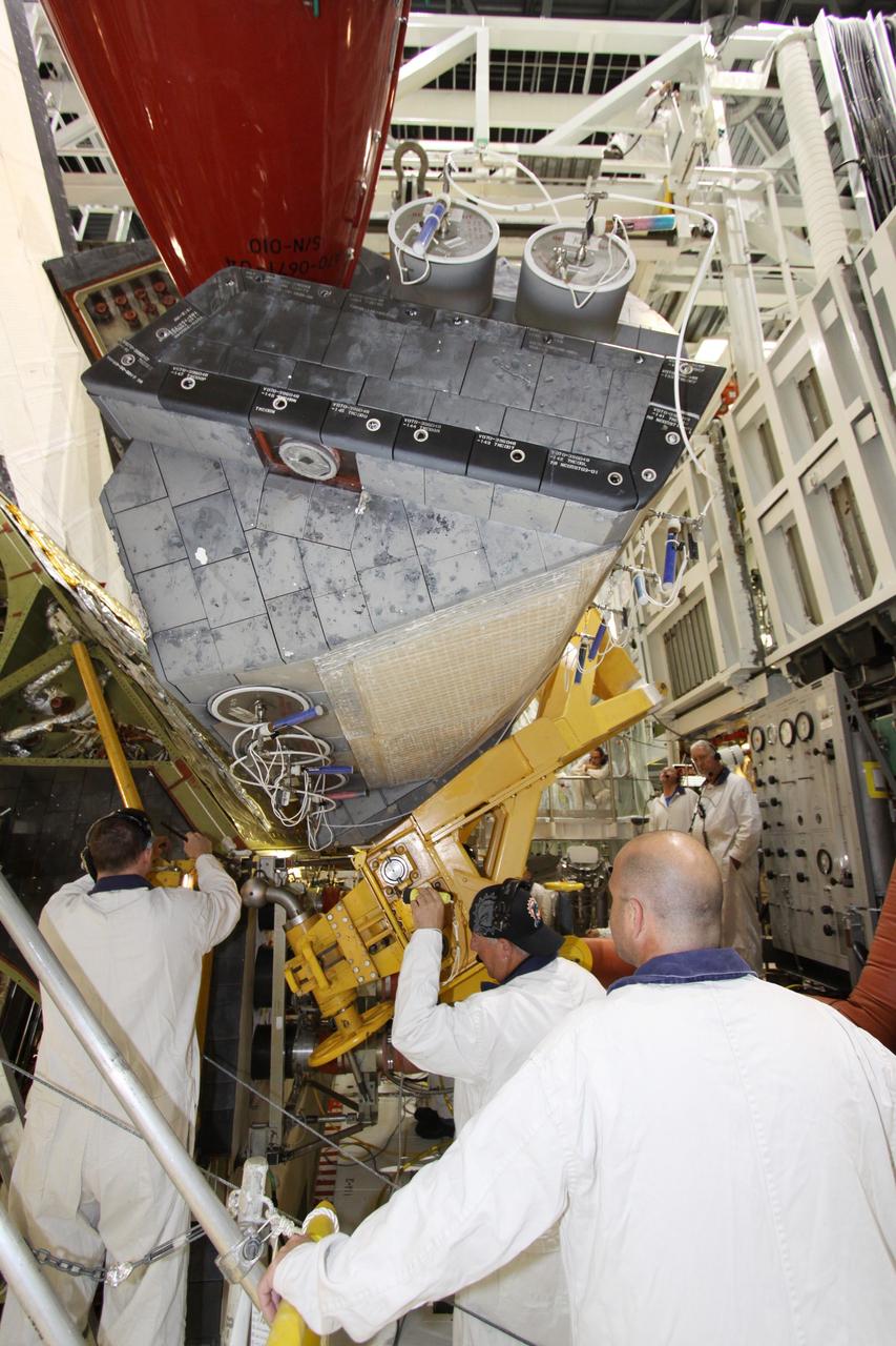 CAPE CANAVERAL, Fla. - In Orbiter Processing Facility-2 at NASA's Kennedy Space Center in Florida, workers use a crane to grapple shuttle Discovery's right-hand orbital maneuvering system, or OMS, pod for removal. It then will be transported to the Hypergol Maintenance Facility. The removal is part of Discovery's transition and retirement processing. Work performed on Discovery is expected to help rocket designers build next-generation spacecraft and prepare the shuttle for future public display. Photo credit: NASA/Jack Pfaller