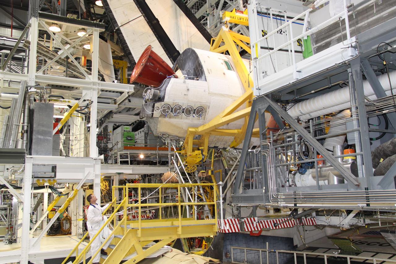 CAPE CANAVERAL, Fla. - In Orbiter Processing Facility-2 at NASA's Kennedy Space Center in Florida, workers use a crane to grapple shuttle Discovery's right-hand orbital maneuvering system, or OMS, pod for removal. It then will be transported to the Hypergol Maintenance Facility. The removal is part of Discovery's transition and retirement processing. Work performed on Discovery is expected to help rocket designers build next-generation spacecraft and prepare the shuttle for future public display. Photo credit: NASA/Jack Pfaller