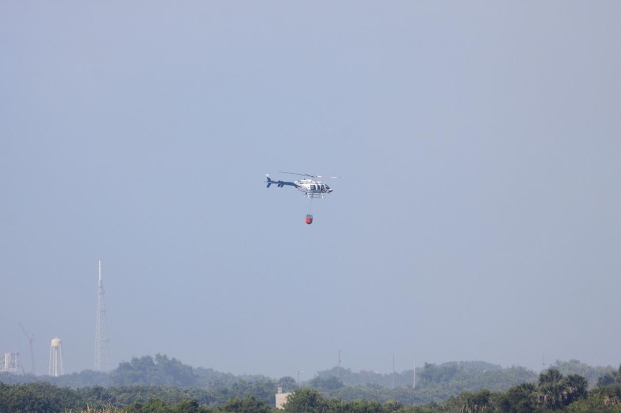 CAPE CANAVERAL, Fla. -- At NASA's Kennedy Space Center in Florida, a helicopter collects water from the Turn Basin to douse a nearby brush fire. The fire was spotted in a rural area southeast of Kennedy’s Press Site approximately three miles away from Launch Pad 39A, where space shuttle Endeavour awaits liftoff on the STS-134 mission to the International Space Station. The fire is being contained by crews from Kennedy and the U.S. Fish and Wildlife Service and smoke is not expected to impact launch. Photo credit: NASA/Jack Pfaller