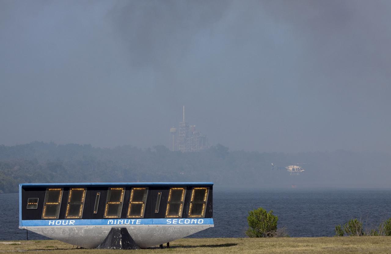 CAPE CANAVERAL, Fla. -- At NASA's Kennedy Space Center in Florida, a helicopter collects water from the Turn Basin to douse a nearby brush fire. The fire was spotted in a rural area southeast of Kennedy’s Press Site approximately three miles away from Launch Pad 39A, where space shuttle Endeavour awaits liftoff on the STS-134 mission to the International Space Station. The fire is being contained by crews from Kennedy and the U.S. Fish and Wildlife Service and smoke is not expected to impact launch. Photo credit: NASA/Jack Pfaller