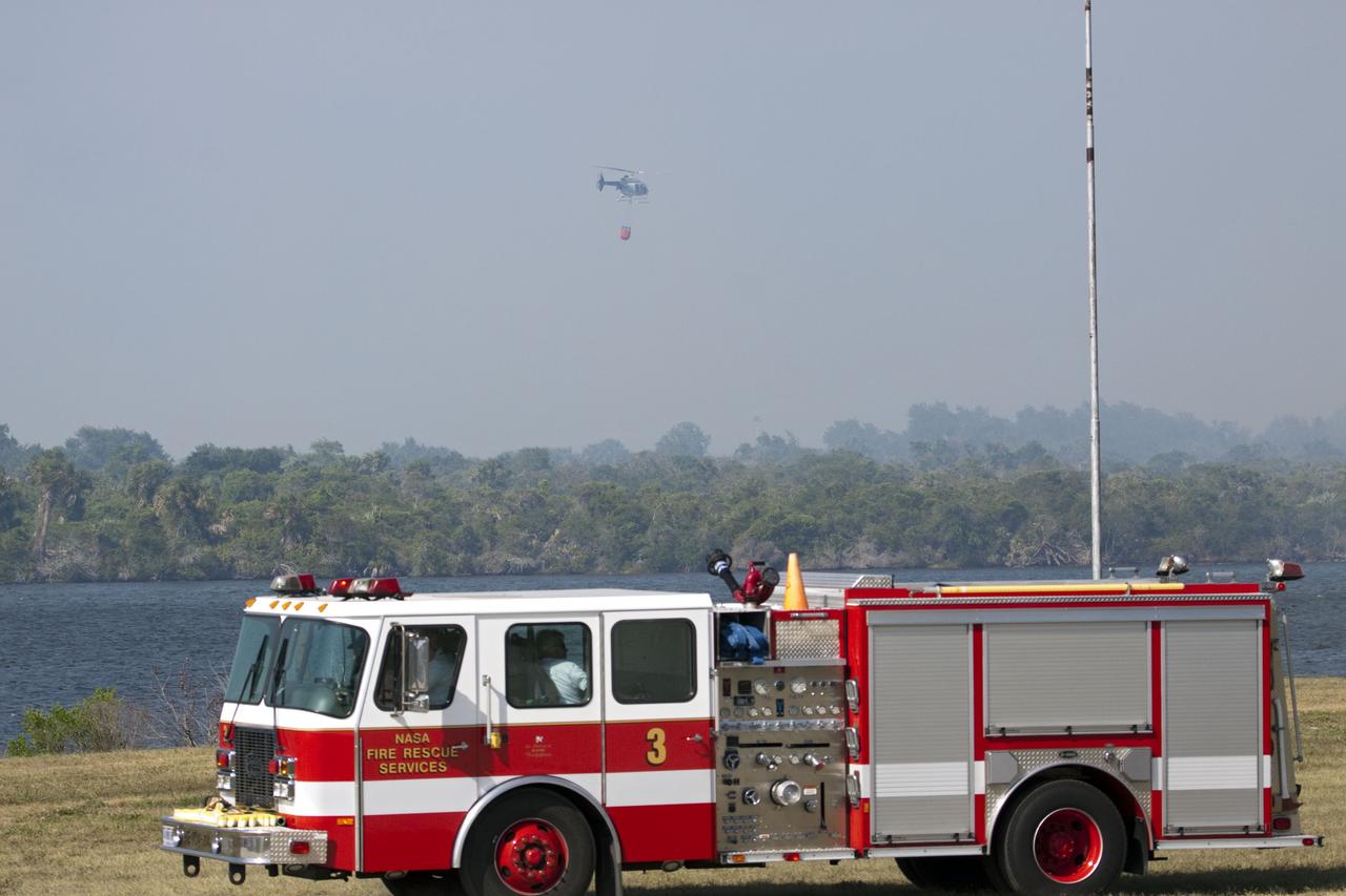 CAPE CANAVERAL, Fla. -- At NASA's Kennedy Space Center in Florida, a helicopter collects water from the Turn Basin to douse a nearby brush fire. The fire was spotted in a rural area southeast of Kennedy’s Press Site approximately three miles away from Launch Pad 39A, where space shuttle Endeavour awaits liftoff on the STS-134 mission to the International Space Station. The fire is being contained by crews from Kennedy and the U.S. Fish and Wildlife Service and smoke is not expected to impact launch. Photo credit: NASA/Jack Pfaller