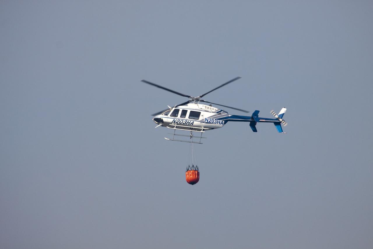 CAPE CANAVERAL, Fla. -- At NASA's Kennedy Space Center in Florida, a helicopter collects water from the Turn Basin to douse a nearby brush fire. The fire was spotted in a rural area southeast of Kennedy’s Press Site approximately three miles away from Launch Pad 39A, where space shuttle Endeavour awaits liftoff on the STS-134 mission to the International Space Station. The fire is being contained by crews from Kennedy and the U.S. Fish and Wildlife Service and smoke is not expected to impact launch. Photo credit: NASA/Jack Pfaller