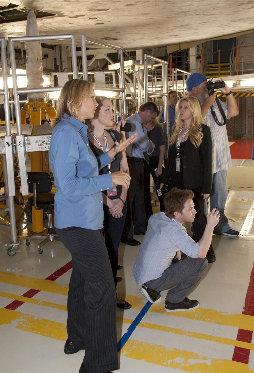 CAPE CANAVERAL, Fla. -- Media representatives participate in a Now and Future Tour at NASA's Kennedy Space Center in Florida. Here, they make a stop in Orbiter Processing Facility-2 (OPF-2) to learn about how shuttle Discovery is being prepared for future public display at the Smithsonian's National Air and Space Museum Steven F. Udvar-Hazy Center in Chantilly, Va. Leading the OPF-2 tour is Discovery's NASA Flow Director Stephanie Stilson. Other stops along the tour included Launch Pad 39B and the Shuttle Landing Facility (SLF). Pad B is being restructured for future use. Its new design will feature a "clean pad" for rockets to come with their own launcher, making it more versatile for a number of vehicles. The SLF's runway could be used for private companies and government agencies to host a diversity of launch systems, including orbital and suborbital flights. Photo credit: NASA/Jack Pfaller
