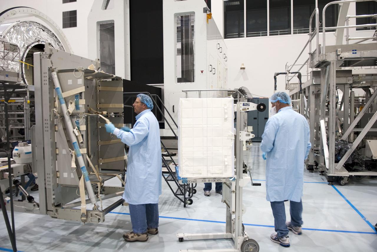 CAPE CANAVERAL, Fla. -- In the Space Station Processing Facility at NASA's Kennedy Space Center in Florida, technicians prepare to load a cargo bag onto a resupply stowage platform. The platform will be installed inside the Raffaello multi-purpose logistics module, in the background at left, for space shuttle Atlantis' flight to the International Space Station.    Atlantis and its payload are being prepared for the STS-135 mission, which will deliver Raffaello packed with supplies and spare parts to the station. STS-135, targeted to launch June 28, will be the 33rd flight of Atlantis, the 37th shuttle mission to the space station, and the 135th and final mission of NASA's Space Shuttle Program. For more information, visit www.nasa.gov/mission_pages/shuttle/shuttlemissions/sts135/index.html. Photo credit: NASA/Jim Grossmann