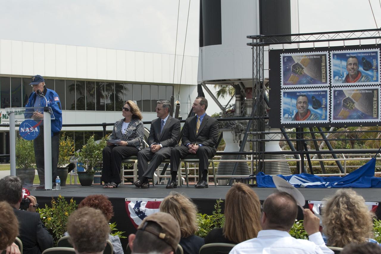 CAPE CANAVERAL, Fla. -- In the Rocket Garden at NASA's Kennedy Space Center Visitor Complex in Florida, Mercury Astronaut Scott Carpenter speaks to the audience gathered for the unveiling of two new stamps that commemorate the 50th anniversary of human spaceflight from the United States Postal Service. Listening to him speak is Director of Education and External Relations for Kennedy, Cheryl Hurst (left), Center Director, Bob Cabana and United States Postal Service Official Steve Massey.      One stamp commemorates NASA's Project Mercury and Alan Shepard's historic launch on May 5, 1961, aboard the spacecraft Freedom 7. The second stamp honors NASA's MESSENGER, which reached Mercury in March to become the first spacecraft to orbit the planet. The two missions frame a remarkable 50-year period in which America advanced space exploration through more than 1,500 crewed and uncrewed flights. Photo credit: NASA/Kim Shiflett