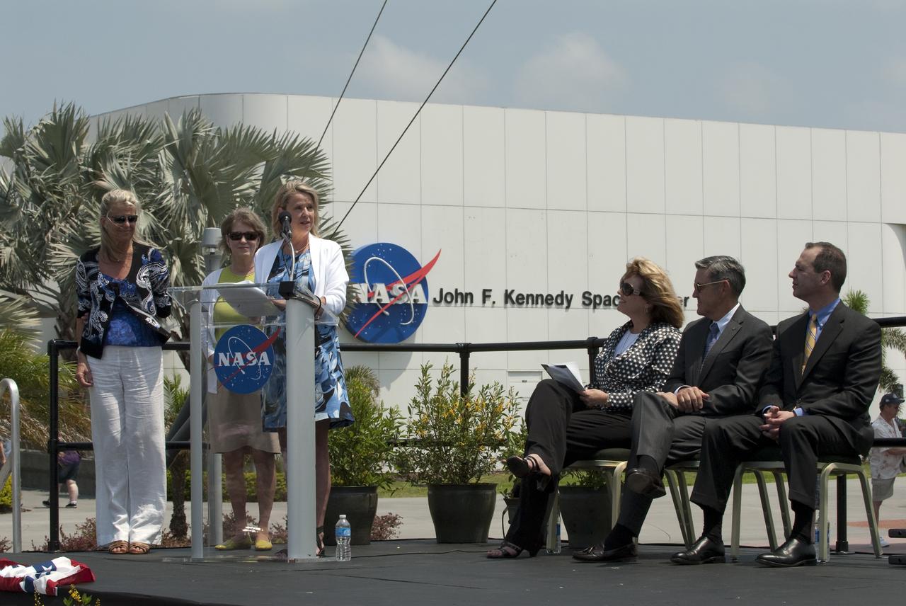 CAPE CANAVERAL, Fla. -- In the Rocket Garden at NASA's Kennedy Space Center Visitor Complex in Florida, Laura Churchley (left), Alice Wackerman and Julie Jenkins, daughters of Mercury Astronaut Alan Shepard, speak to the audience in attendance for the United States Postal Service unveiling of two new stamps to commemorate the 50th anniversary of human spaceflight. Listening to them speak is Director of Education and External Relations for Kennedy, Cheryl Hurst (left), Kennedy Center Director, Bob Cabana and United States Postal Service official Steve Massey.            One stamp commemorates NASA's Project Mercury and Alan Shepard's historic launch on May 5, 1961, aboard the spacecraft Freedom 7. The second stamp honors NASA's MESSENGER, which reached Mercury in March to become the first spacecraft to orbit the planet. The two missions frame a remarkable 50-year period in which America advanced space exploration through more than 1,500 crewed and uncrewed flights. Photo credit: NASA/Kim Shiflett