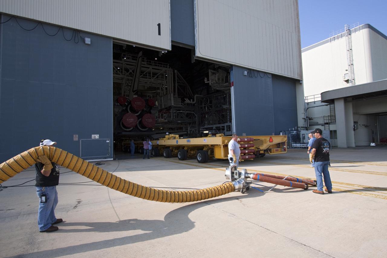 CAPE CANAVERAL, Fla. -- Workers prepare to attach an exhaust hose to the Orbiter Transporter System (OTS) at Orbiter Processing Facility-1 at NASA's Kennedy Space Center in Florida. The OTS is being moved under shuttle Atlantis for its rollover to the nearby Vehicle Assembly Building (VAB).      Once inside the VAB, Atlantis will be joined to its solid rocket boosters and external fuel tank on the mobile launcher platform. Later this month, Atlantis is scheduled to "rollout" to Launch Pad 39A on the STS-135 mission, which will deliver the Raffaello multi-purpose logistics module packed with supplies and spare parts to the International Space Station. STS-135, targeted to launch June 28, will be the 33rd flight of Atlantis, the 37th shuttle mission to the station, and the 135th and final mission of NASA's Space Shuttle Program. For more information, visit www.nasa.gov/mission_pages/shuttle/shuttlemissions/sts135/index.html. NASA/Jack Pfaller