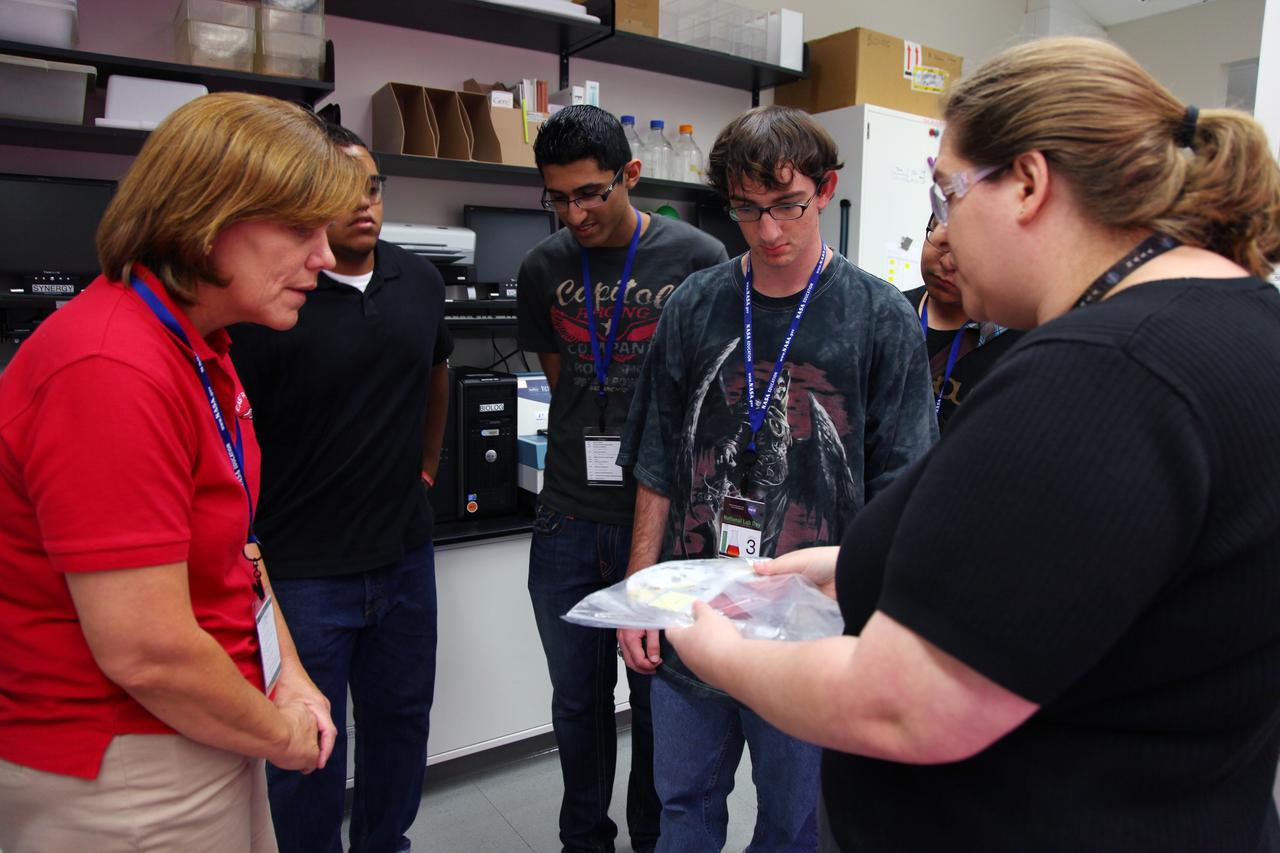 Cape Canaveral, Fla. -- Students listen intently as a laboratory technician describes a project that's being researched in Kennedy’s Space Life Sciences Laboratory (SLSL). High-school students from two Orlando, Fla., schools travelled to NASA’s Kennedy Space Center in Florida to participate in National Lab Day activities. During the event, about 80 students, toured various facilities and engaged in educational hands-on activities. National Lab Day is a partnership between federal agencies, foundations, professional societies and organizations devoted to promoting science, technology, engineering and math, or STEM, hands-on discovery-based laboratory experiences for students. Photo Credit: NASA/Frankie Martin