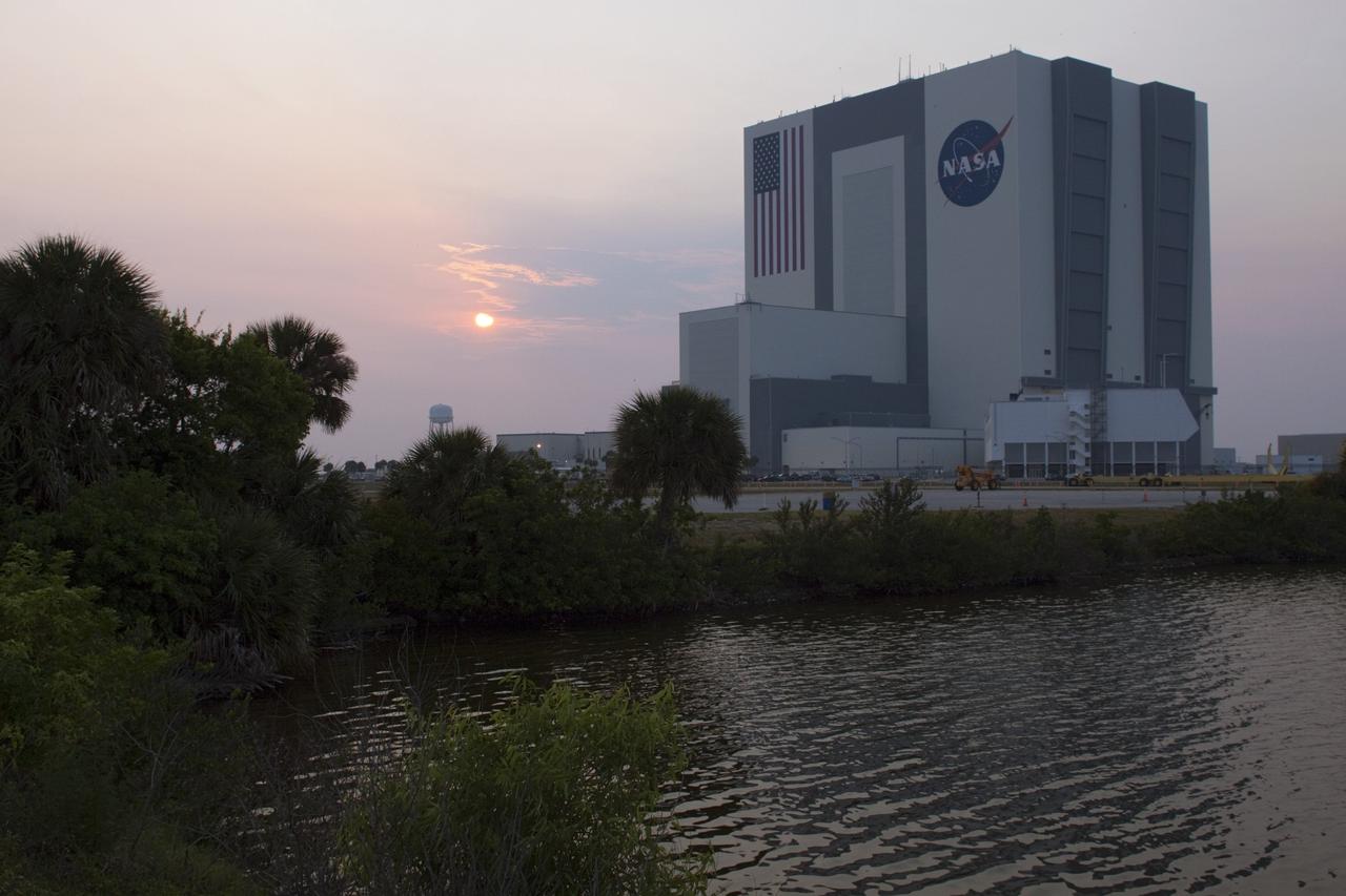 Cape Canaveral, Fla. -- The sunrise casts a haze over the Shuttle Landing Facility and the Vehicle Assembly Building at NASA's Kennedy Space Center in Florida, where the arrival of NASA's Mars Science Laboratory (MSL) first three elements are being delivered by an Air Force C-17 cargo plane.      The cruise stage, back shell and heat shield, the first flight elements to arrive for the MSL mission, were taken to the Payload Hazardous Servicing Facility (PHSF) located in the KSC Industrial Area to begin processing. The Curiosity rover will arrive next month.     A United Launch Alliance Atlas V-541 configuration will be used to loft MSL into space. Curiosity’s 10 science instruments are designed to search for evidence on whether Mars has had environments favorable to microbial life, including chemical ingredients for life.  The unique rover will use a laser to look inside rocks and release its gasses so that the rover’s spectrometer can analyze and send the data back to Earth. MSL is scheduled to launch from Cape Canaveral Air Force Station in Florida Nov. 25 with a window extending to Dec. 18 and arrival at Mars Aug. 2012. For more information, visit http://www.nasa.gov/msl. Photo credit: NASA/Troy Cryder