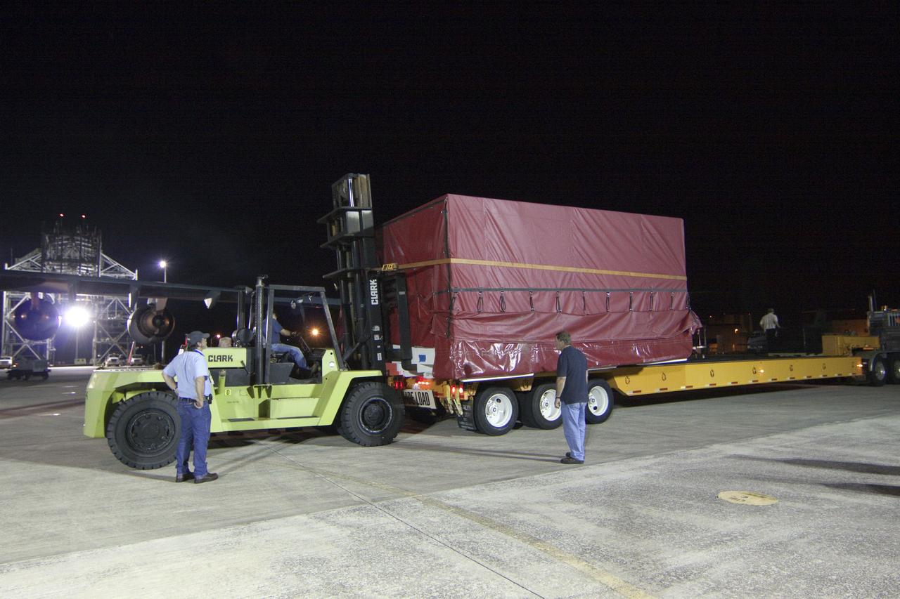 CAPE CANAVERAL, Fla. -- Workers load onto a transporter a container holding the heat shield, one of the first three elements for NASA's Mars Science Laboratory (MSL), that arrived at NASA Kennedy Space Center's Shuttle Landing Facility.        The cruise stage, back shell and heat shield, the first flight elements to arrive for the MSL mission, were taken to the Payload Hazardous Servicing Facility (PHSF) located in the KSC Industrial Area to begin processing. The Curiosity rover will arrive next month.     A United Launch Alliance Atlas V-541 configuration will be used to loft MSL into space. Curiosity’s 10 science instruments are designed to search for evidence on whether Mars has had environments favorable to microbial life, including chemical ingredients for life.  The unique rover will use a laser to look inside rocks and release its gasses so that the rover’s spectrometer can analyze and send the data back to Earth. MSL is scheduled to launch from Cape Canaveral Air Force Station in Florida Nov. 25 with a window extending to Dec. 18 and arrival at Mars Aug. 2012. For more information, visit http://www.nasa.gov/msl. Photo credit: NASA/Troy Cryder